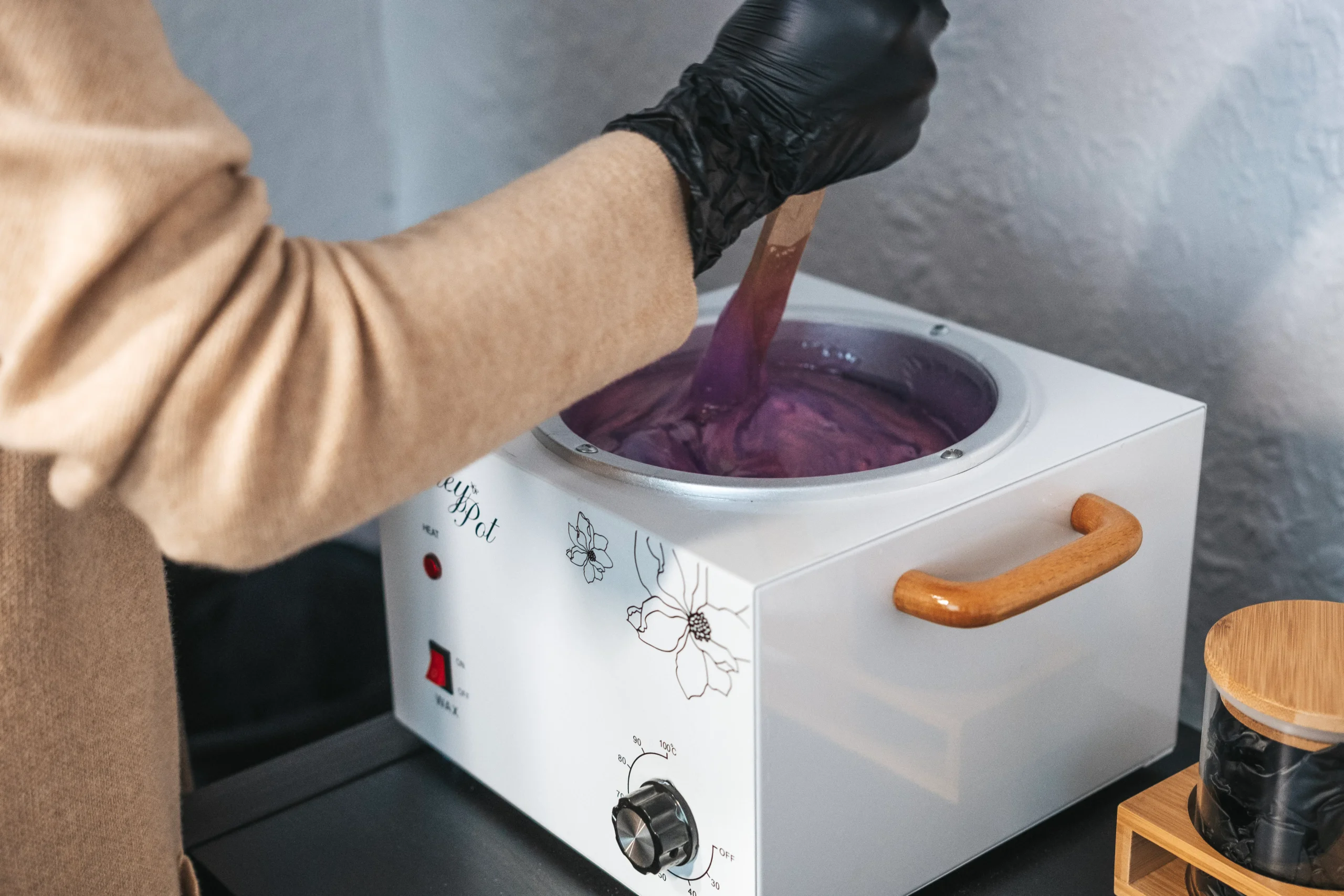An esthetician applying warm wax to a client's leg in a waxing salon, highlighting the technique and precision involved in professional waxing.