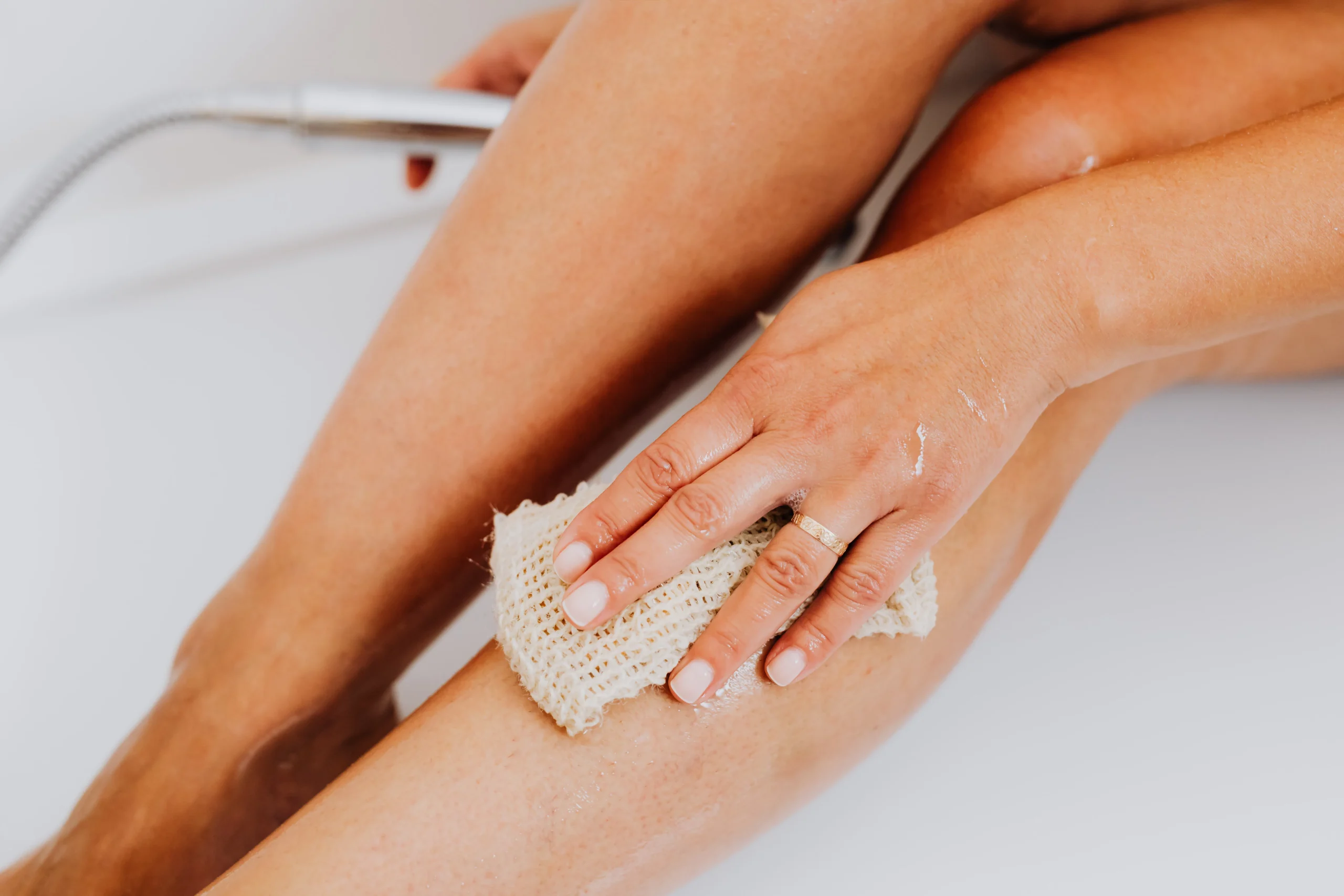 A person gently exfoliating their legs with a scrub and then applying a soothing lotion. Focus on the gentle motions and the nourishing aspect of skincare for legs.