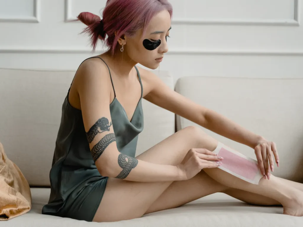 A close-up shot of perfectly smooth, hair-free legs, possibly with a woman applying lotion or showcasing the results of waxing. The background is soft and inviting, suggesting pampering and self-care.