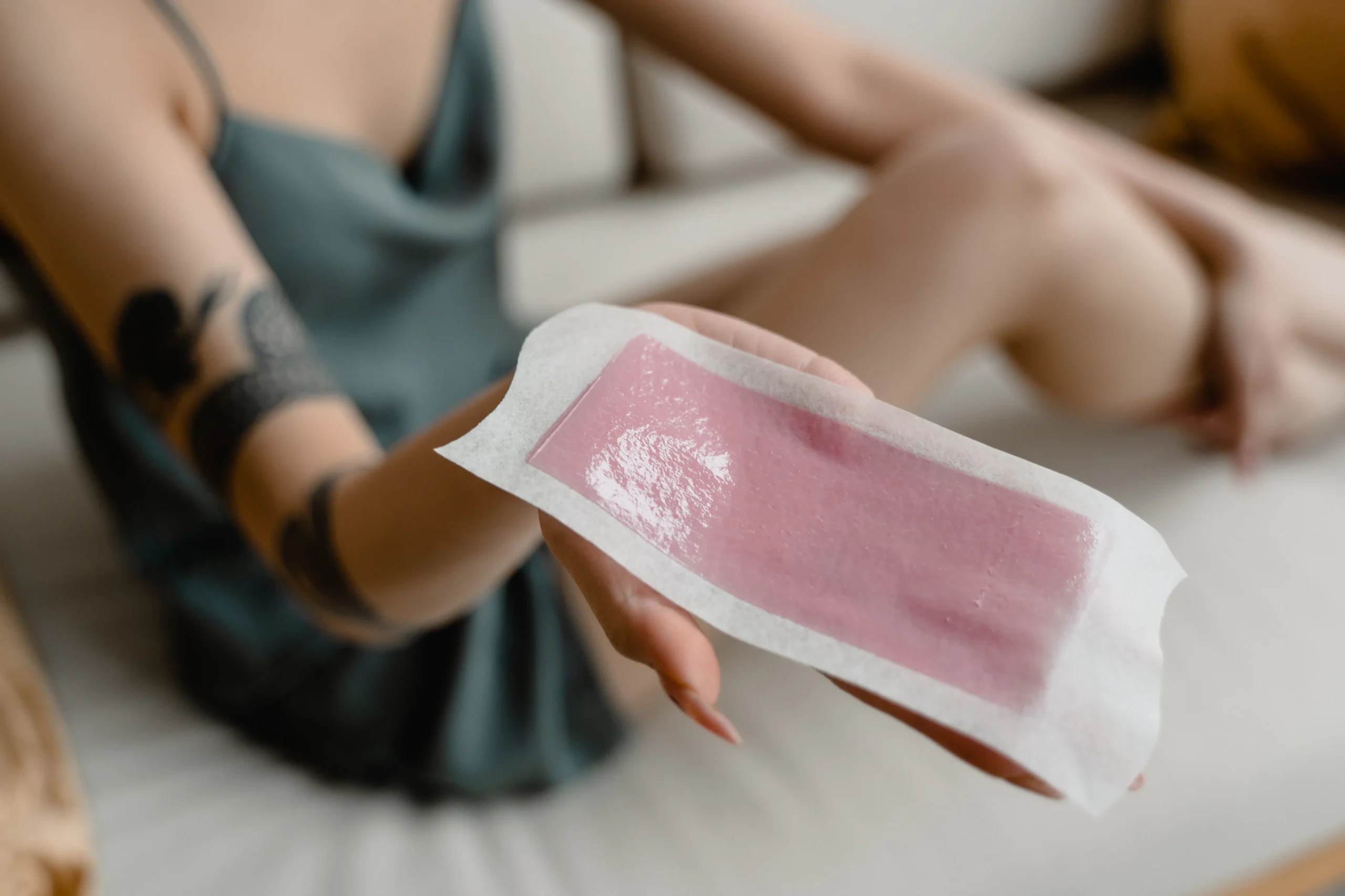Collage of images representing the key steps in the waxing process: exfoliation, wax application, hair removal, and moisturizing. Keywords: waxing guide, smooth skin tips, hair removal process, skin care routine