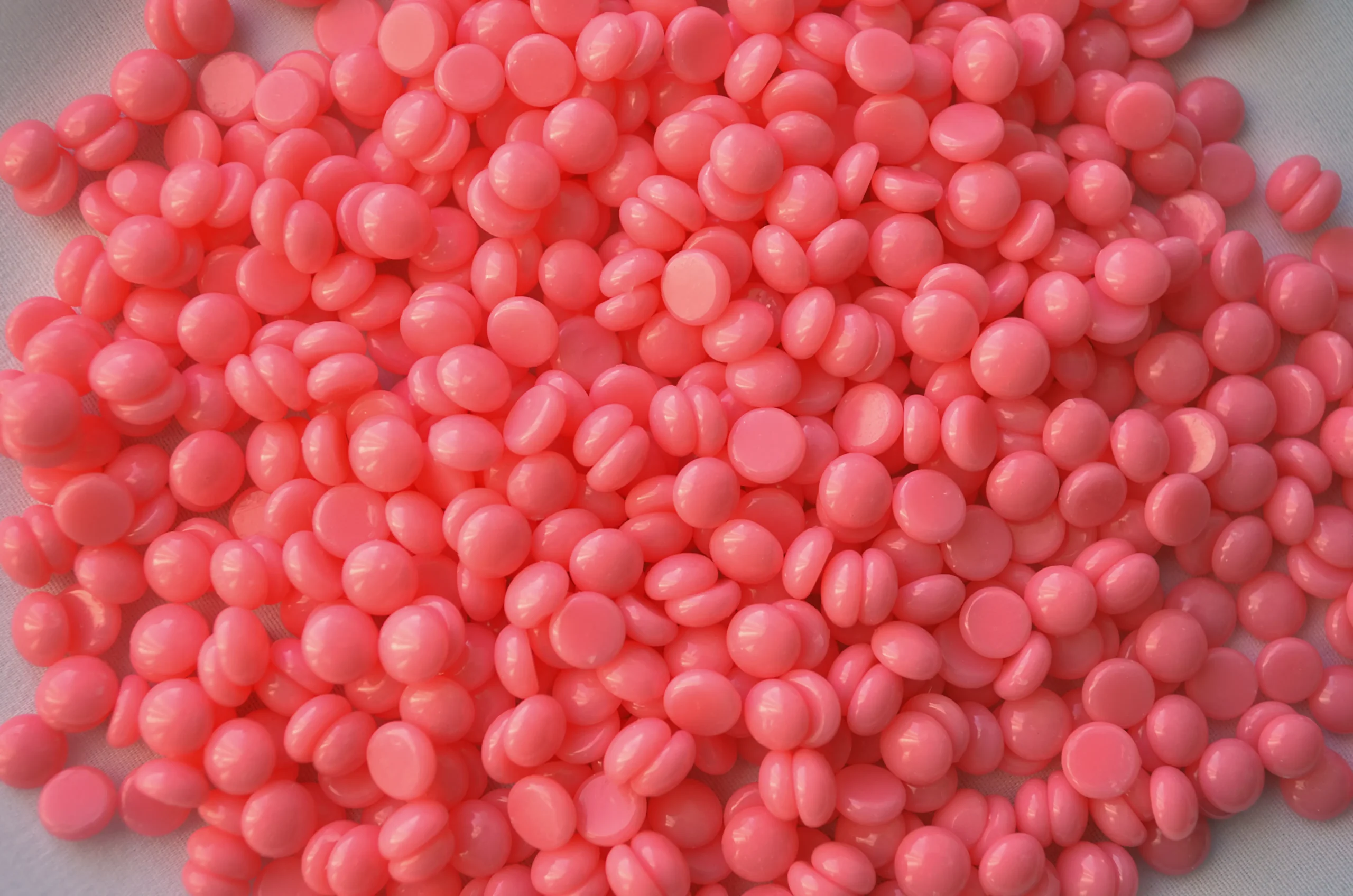 A large quantity of pink hard wax beads, commonly used for leg waxing and other hair removal treatments.