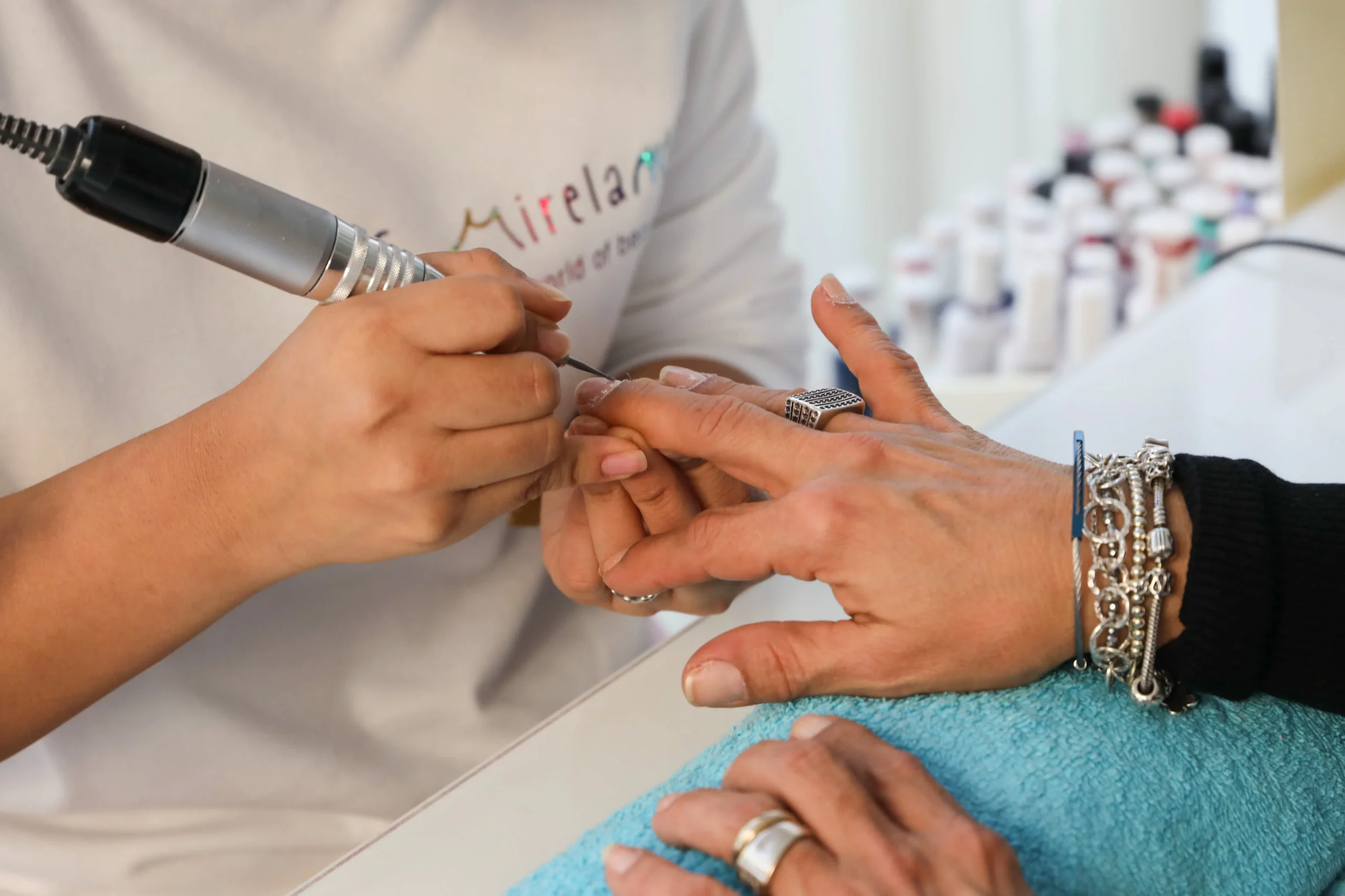 A manicurist delicately works on a client's nails, showcasing attention to detail in nail care and beauty treatments.