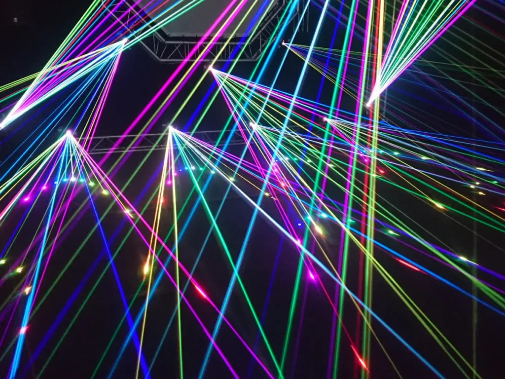 A vibrant display of colorful laser lights crisscrossing and converging, creating a dynamic and energetic visual spectacle.