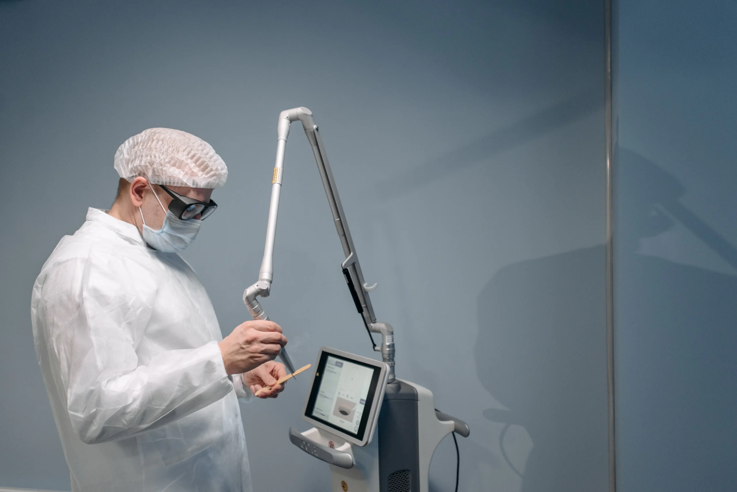 An esthetician performing laser waxing on a client's leg, highlighting the use of advanced laser technology.