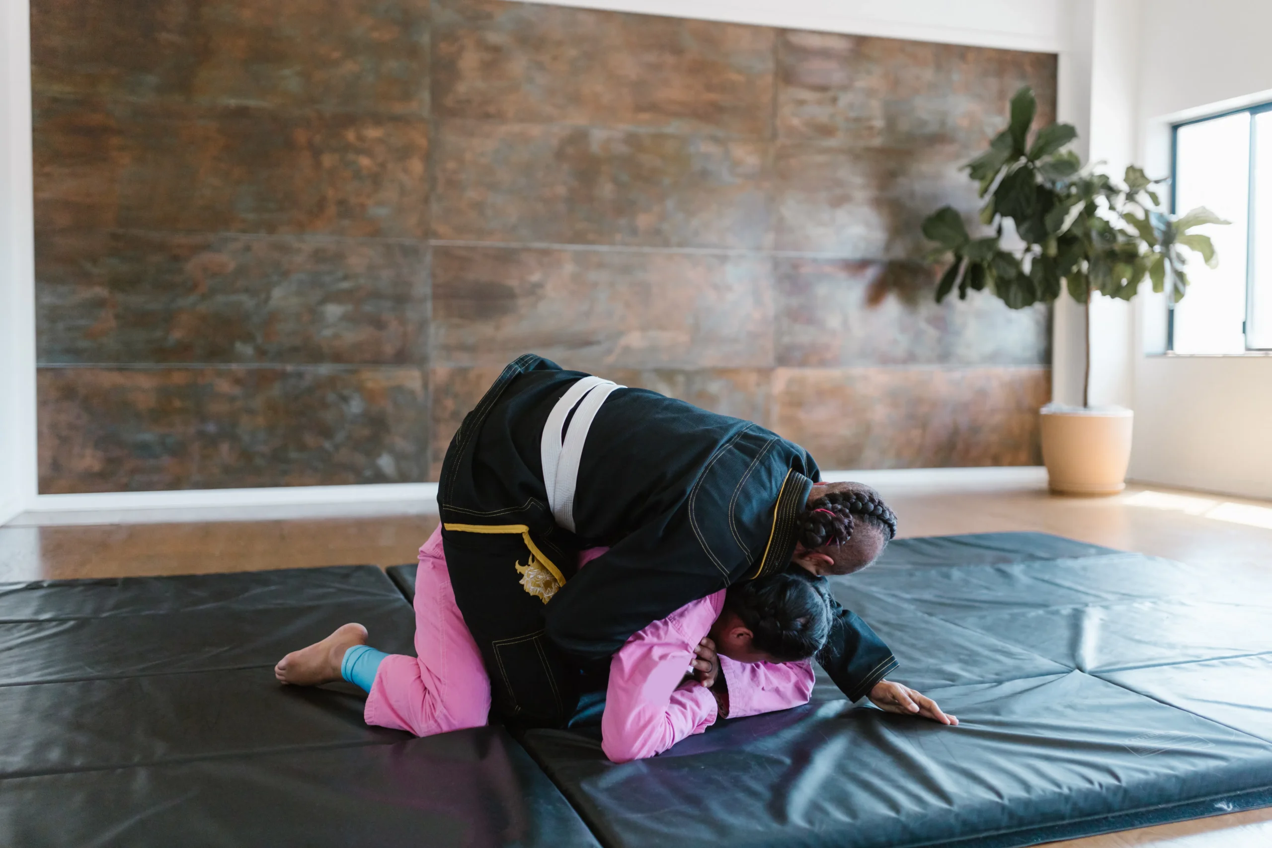 Two people engaged in a grappling martial art on a mat, showcasing a dynamic physical interaction.