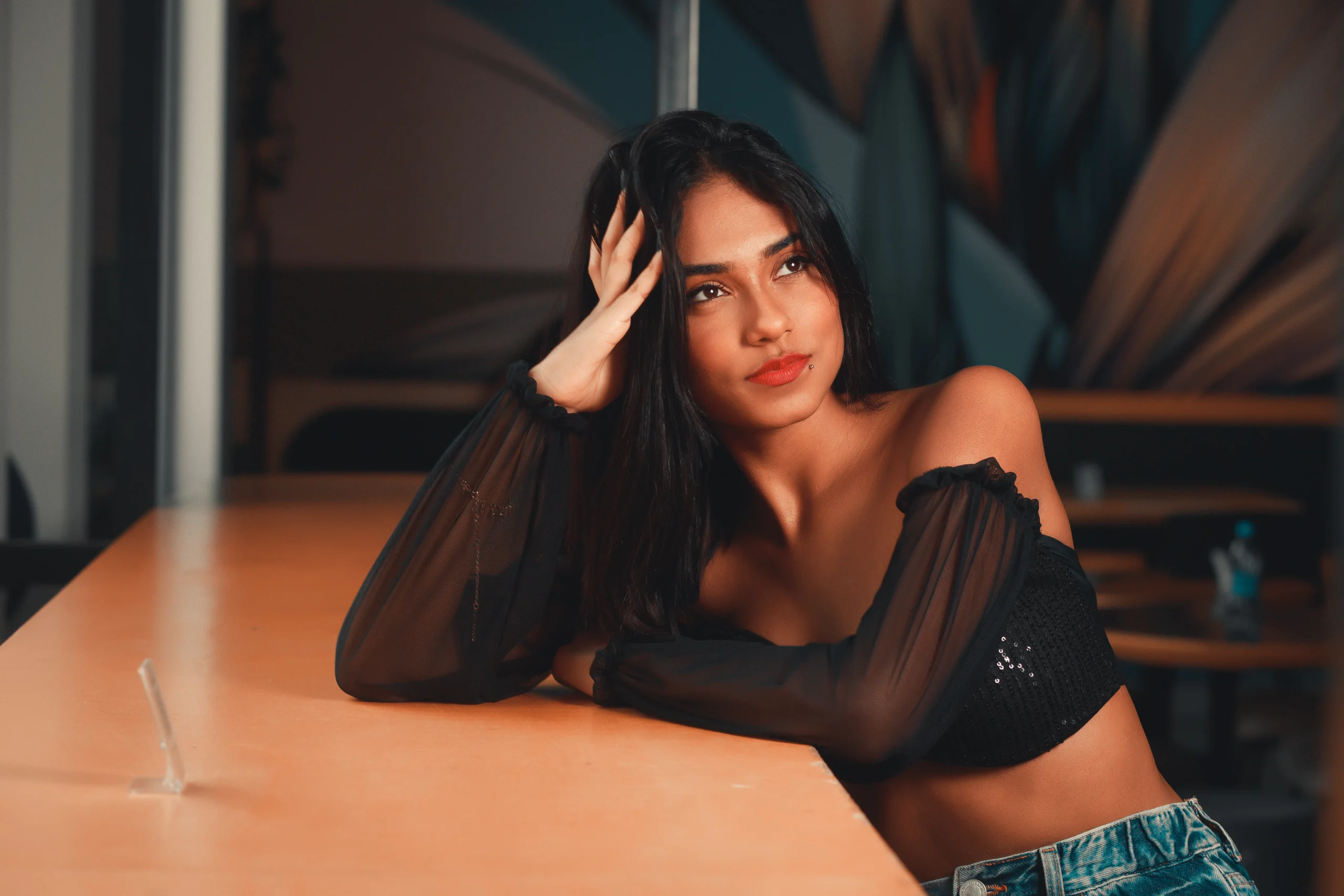 Woman in off-shoulder top resting on table, looking away