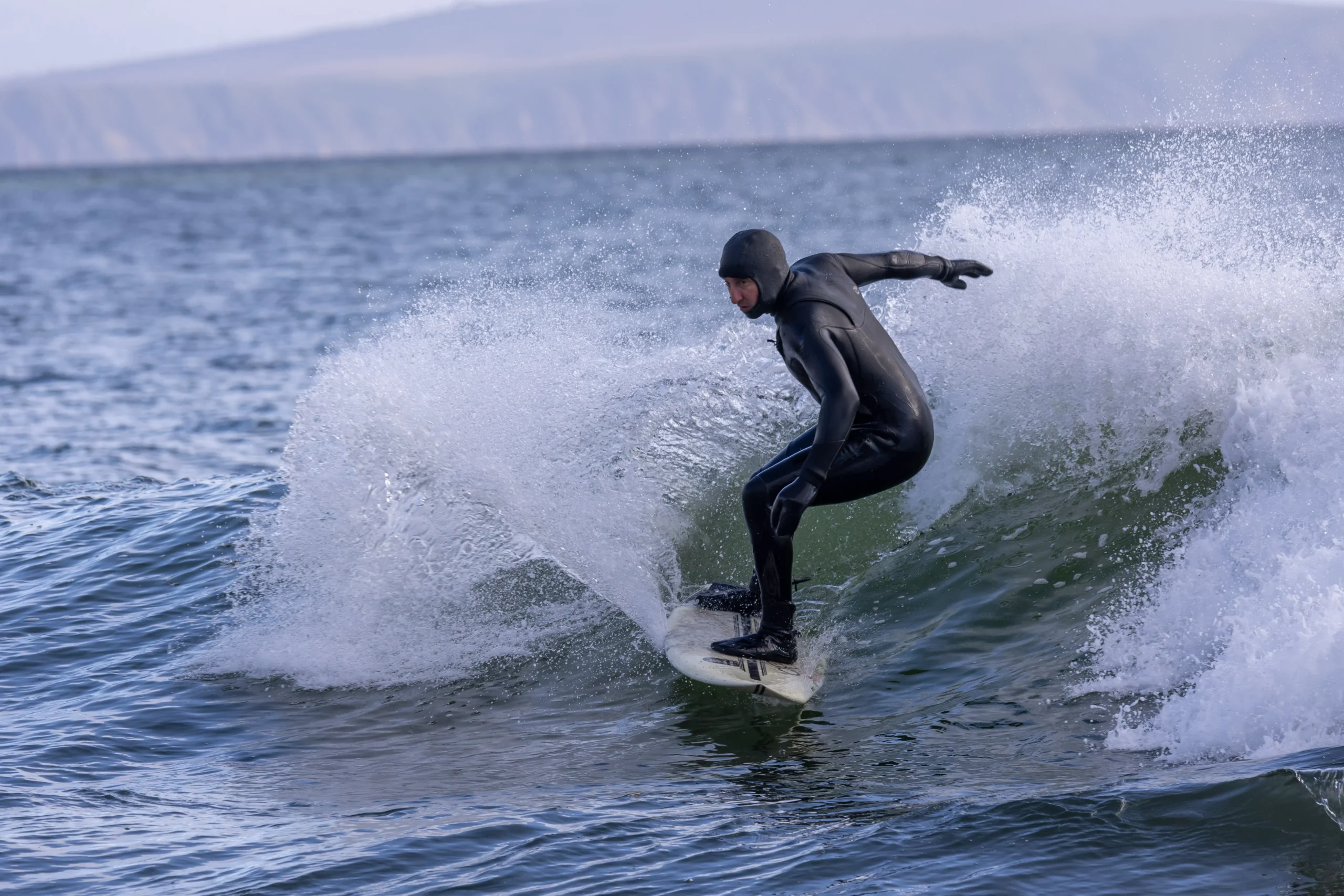 Surfer in black wetsuit riding a wave in the ocean.
