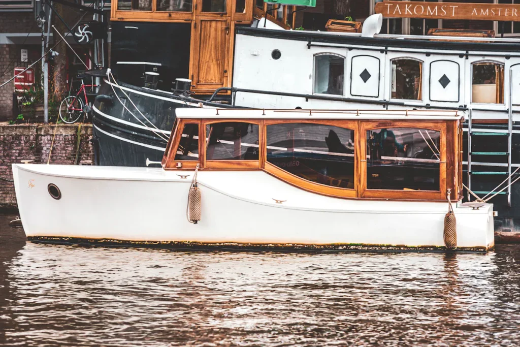 Amsterdam canal boat with wooden trim near Takomst Amsterdam sign.