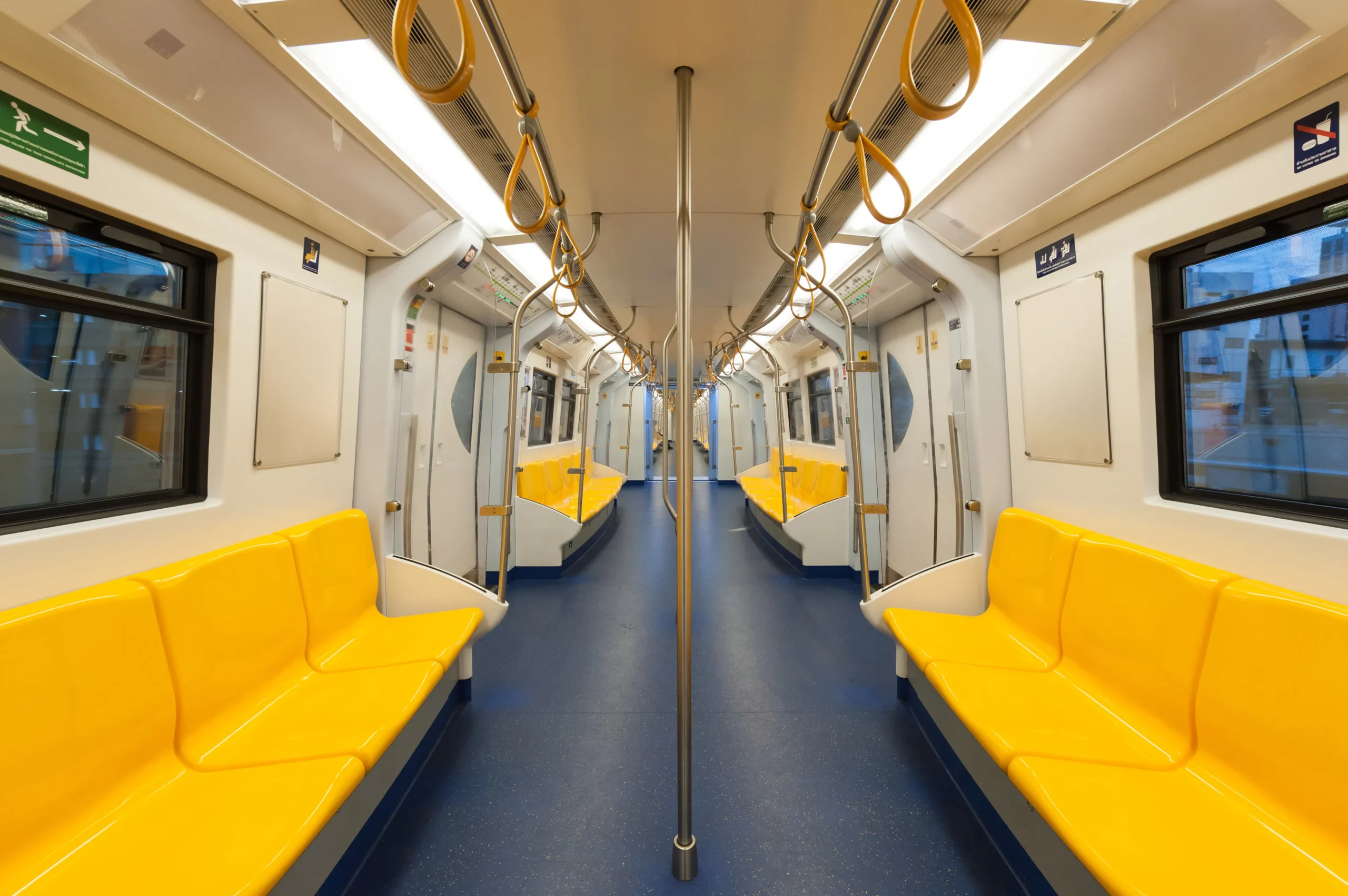 Interior of a modern subway car with yellow seats and blue floor.