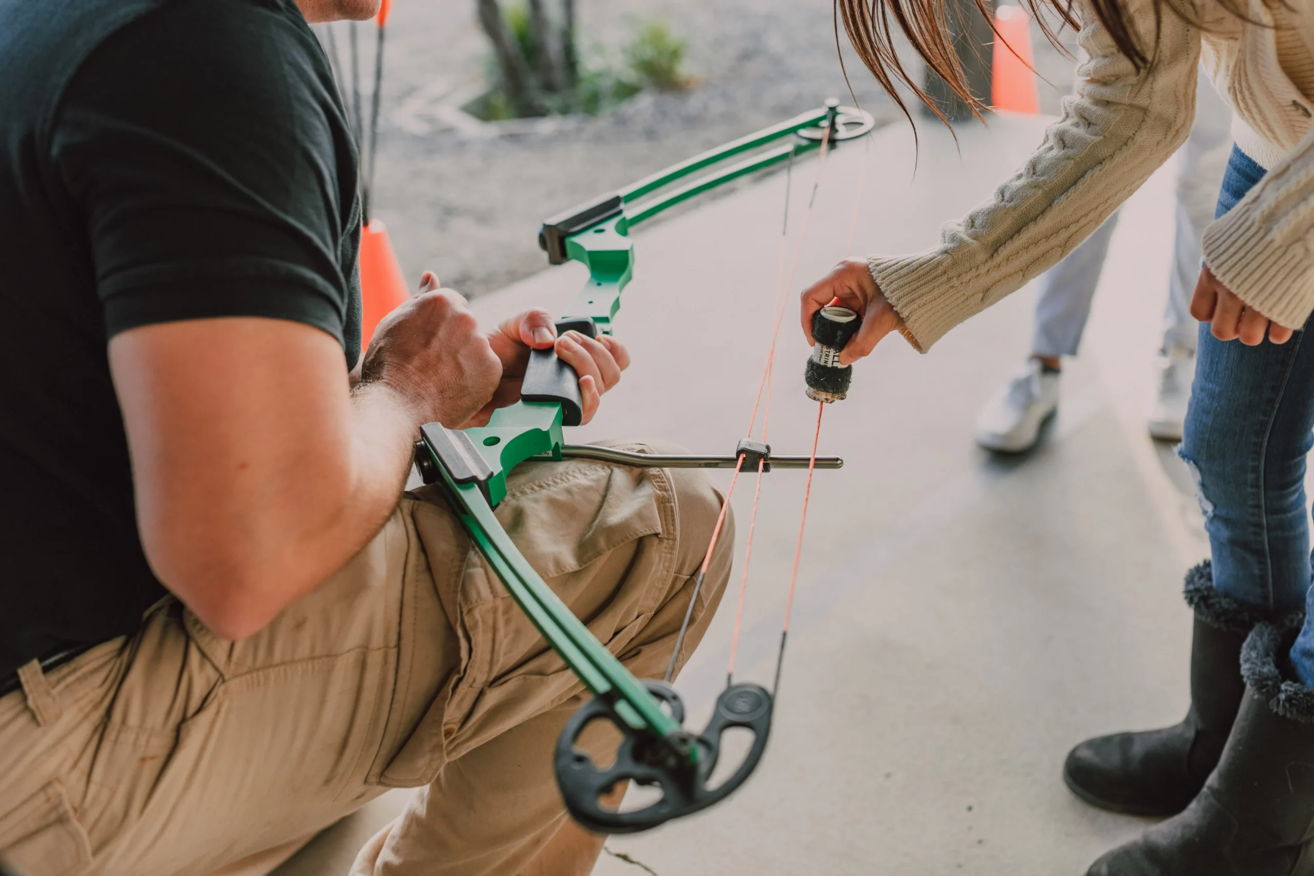 Man holding a green compound bow, preparing for target practice.