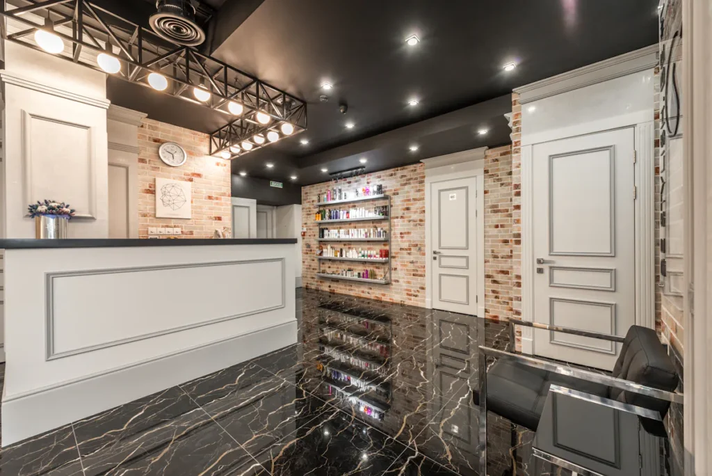 Modern Amsterdam beauty salon reception area with product shelves and black marble floors.