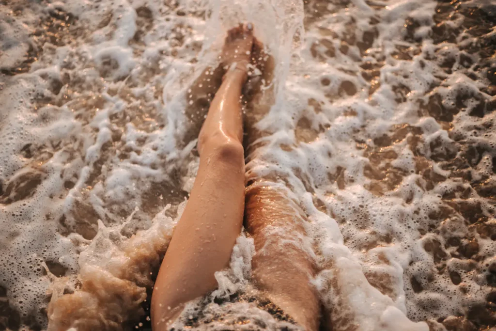Legs submerged in the ocean water, showcasing summer leg prep and smooth legs.
