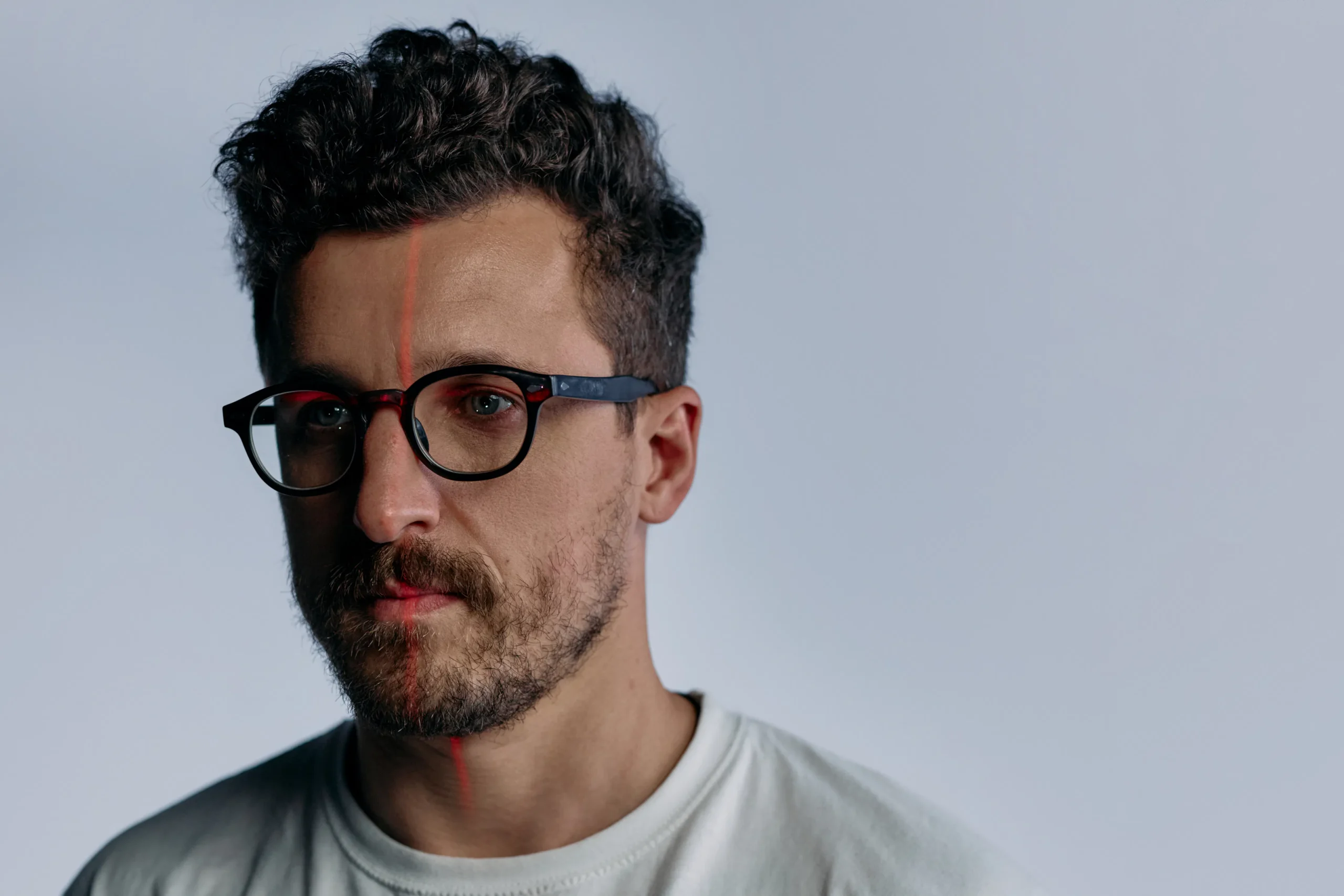 Man's face with glasses and red laser line, facial laser hair removal