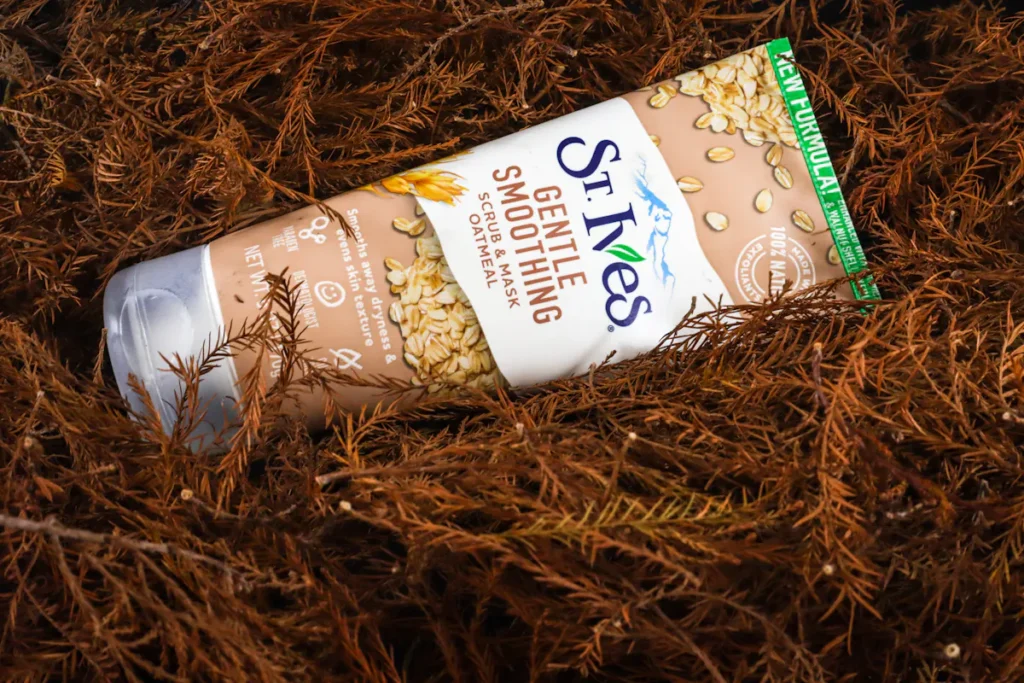 St. Ives Gentle Smoothing Oatmeal Scrub & Mask tube on brown foliage, for skin care.