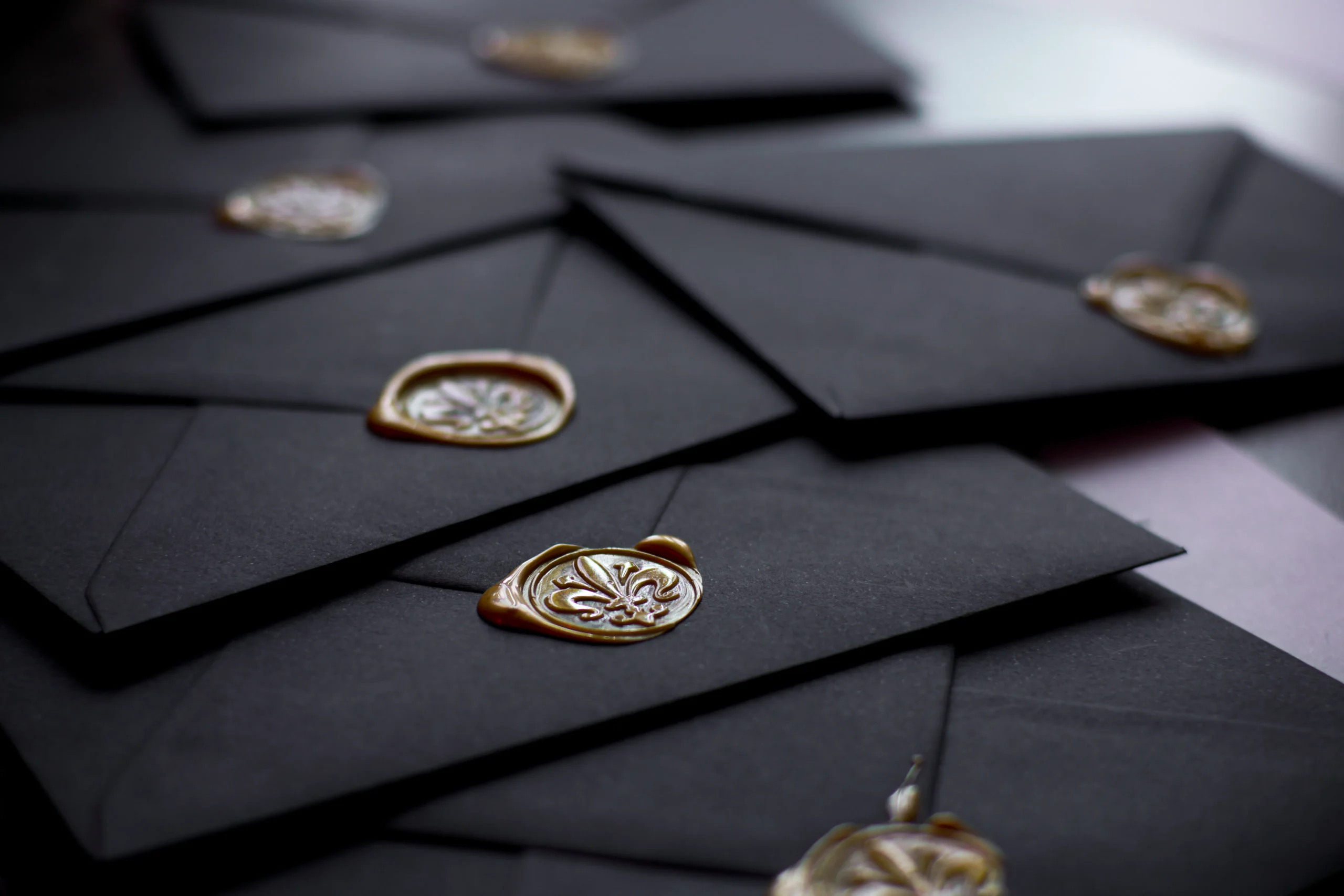 Close-up of black envelopes sealed with ornate gold wax seals