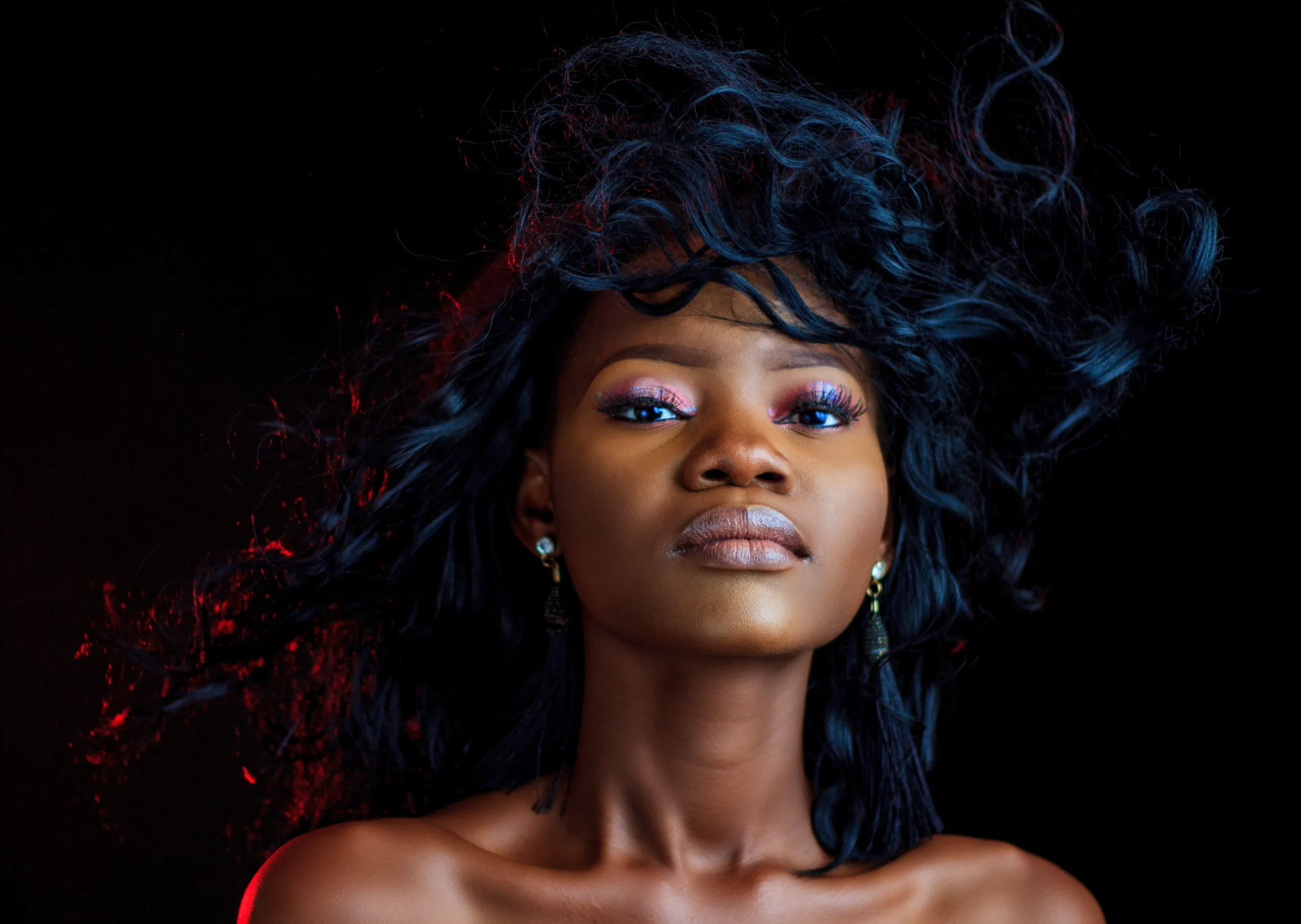 Portrait of a woman with dark curly hair against a black background.