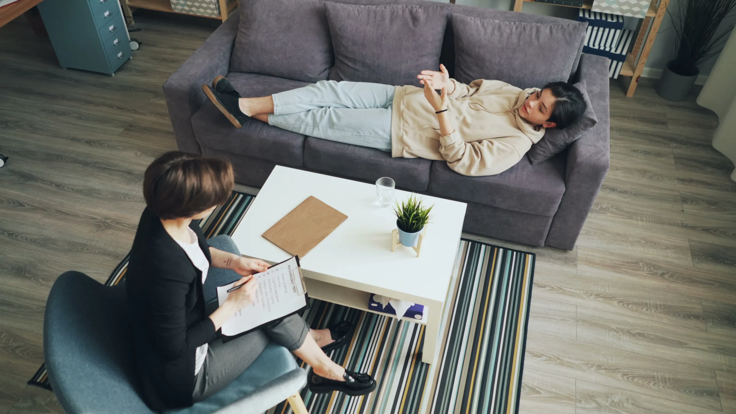 Woman lying on a couch talking with a therapist in an office.