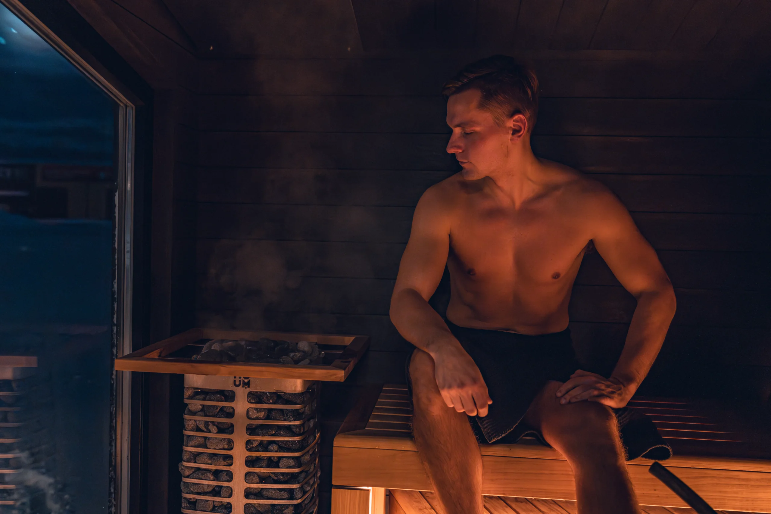 Man in a sauna with rocks and steam, relaxing after effective hair removal.