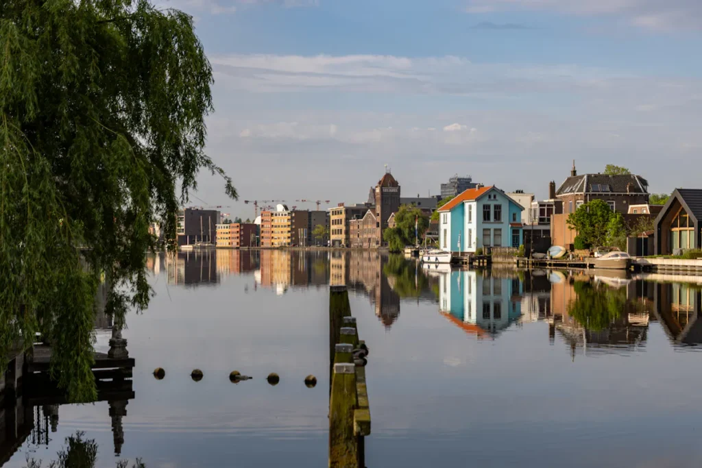 Amsterdam cityscape reflected in calm water, showcasing buildings and architecture.