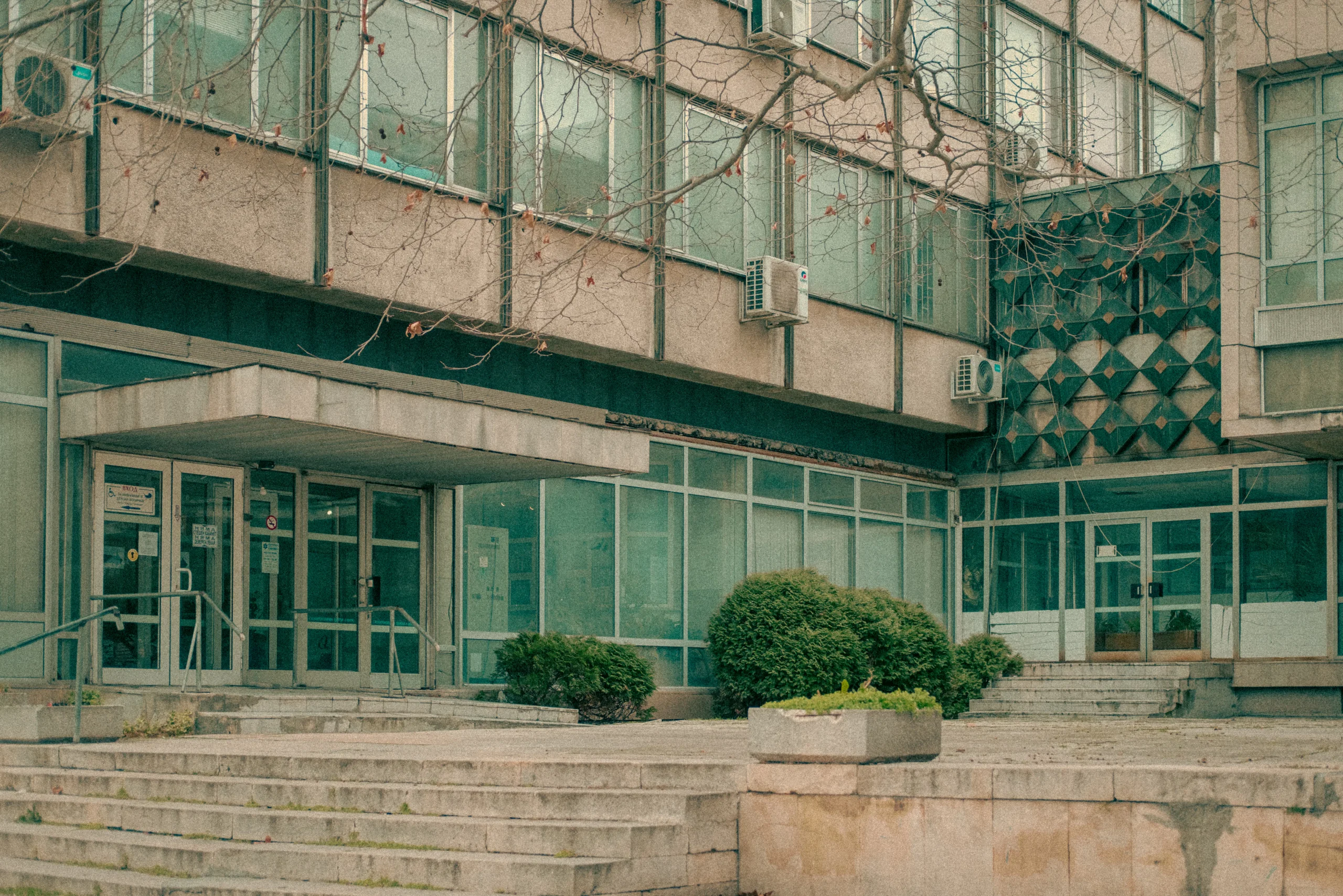 Exterior of a concrete building with multiple windows and sparse winter trees