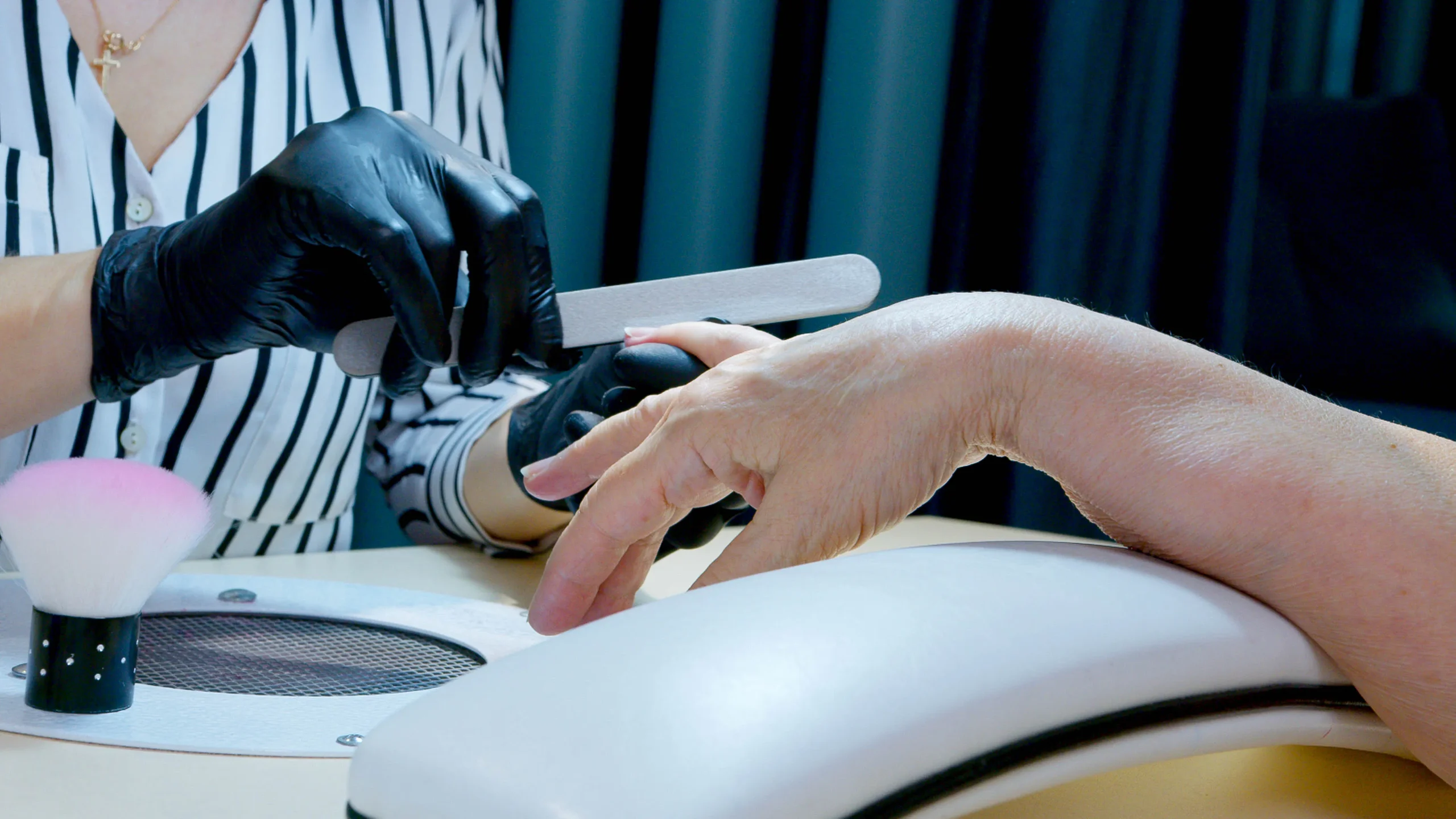 Esthetician files a client's nails, preparing for a flawless wax in Amsterdam.