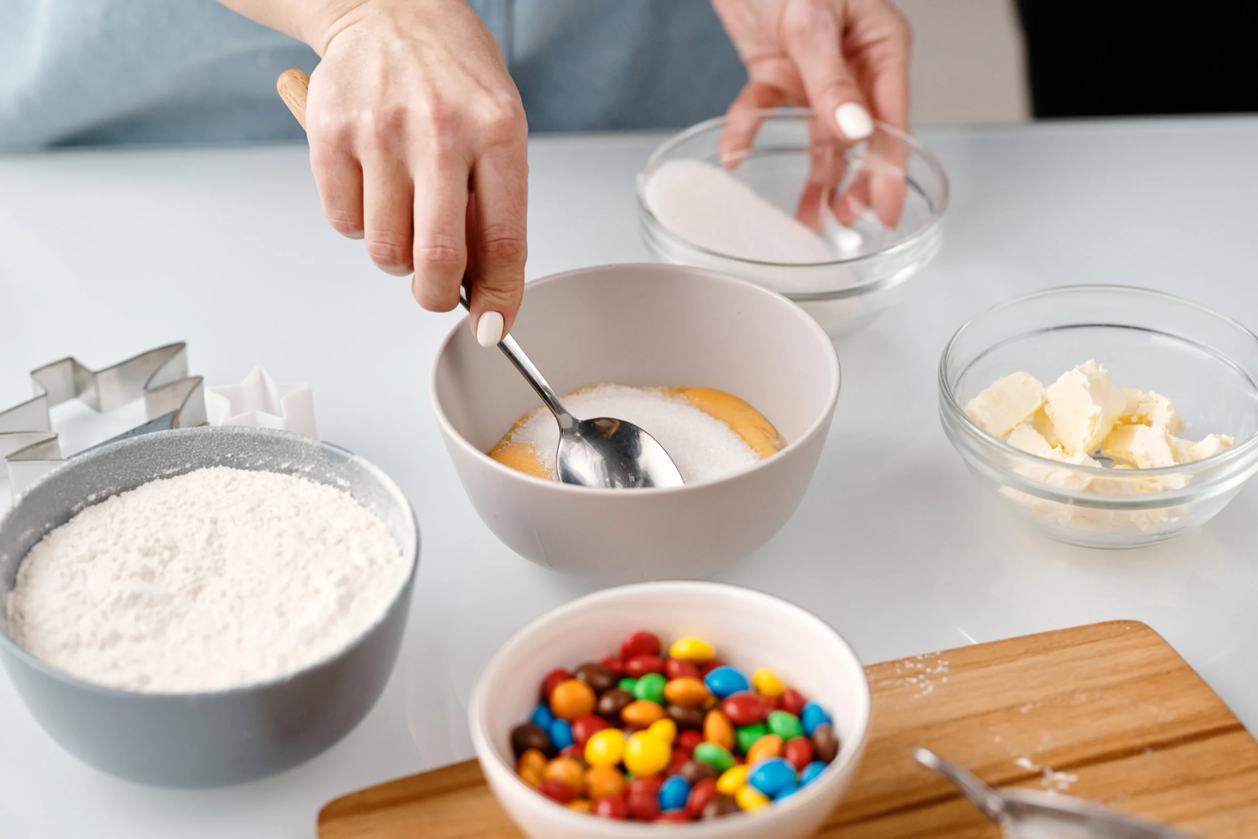 Person mixing ingredients in a bowl, including sugar, eggs, and flour.