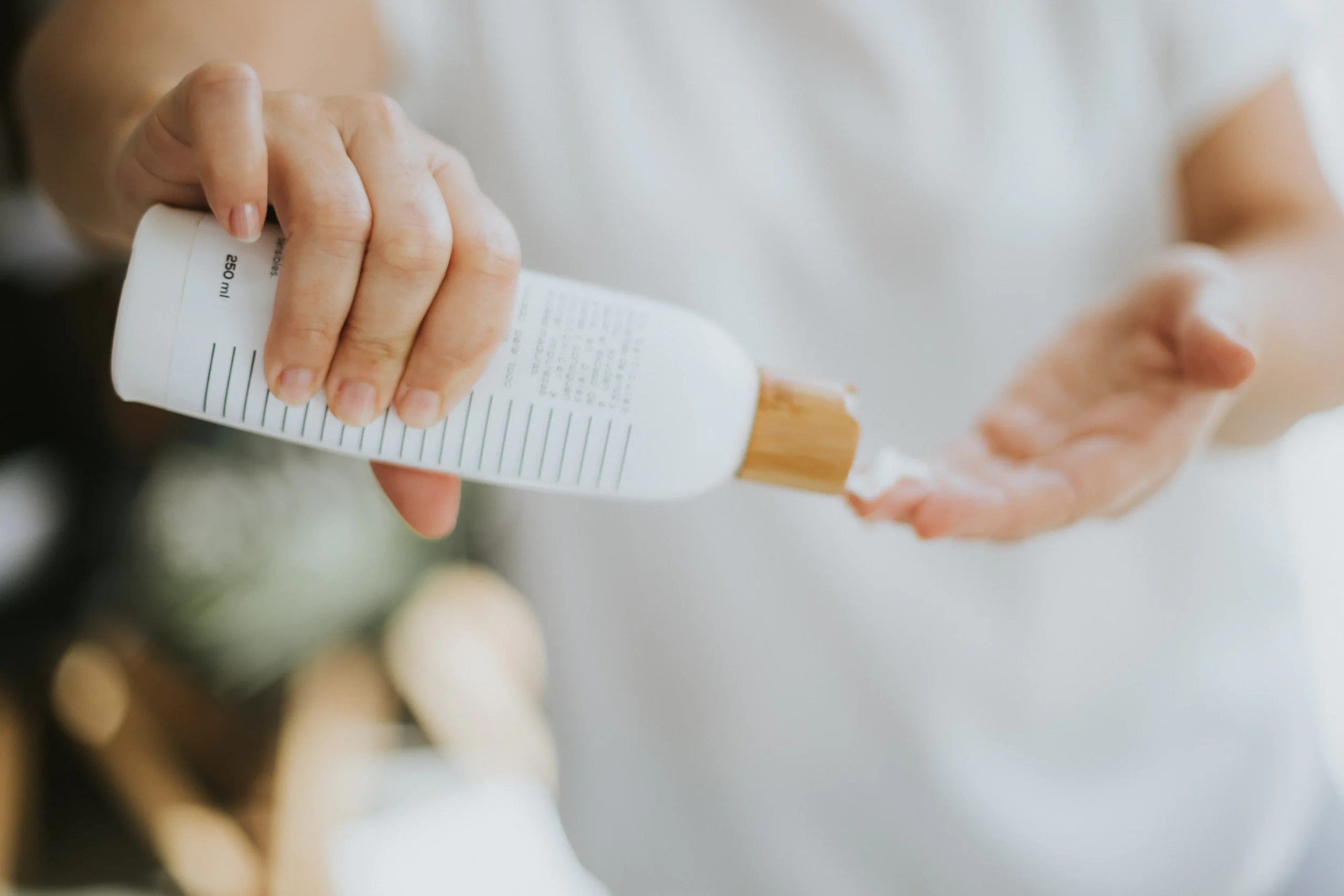 Person dispensing body lotion after full body wax, for smooth skin results.