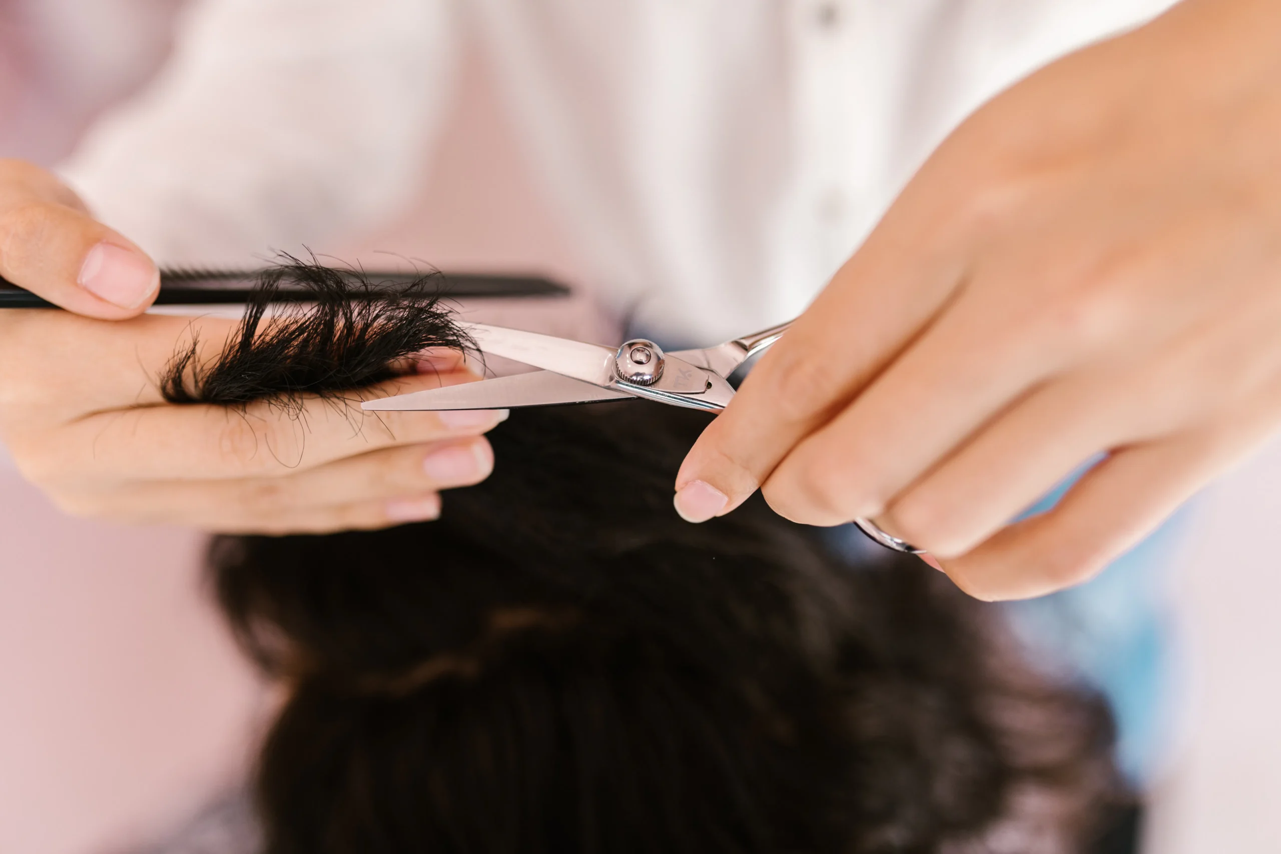 Stylist trimming dark hair with scissors and comb in an Amsterdam salon