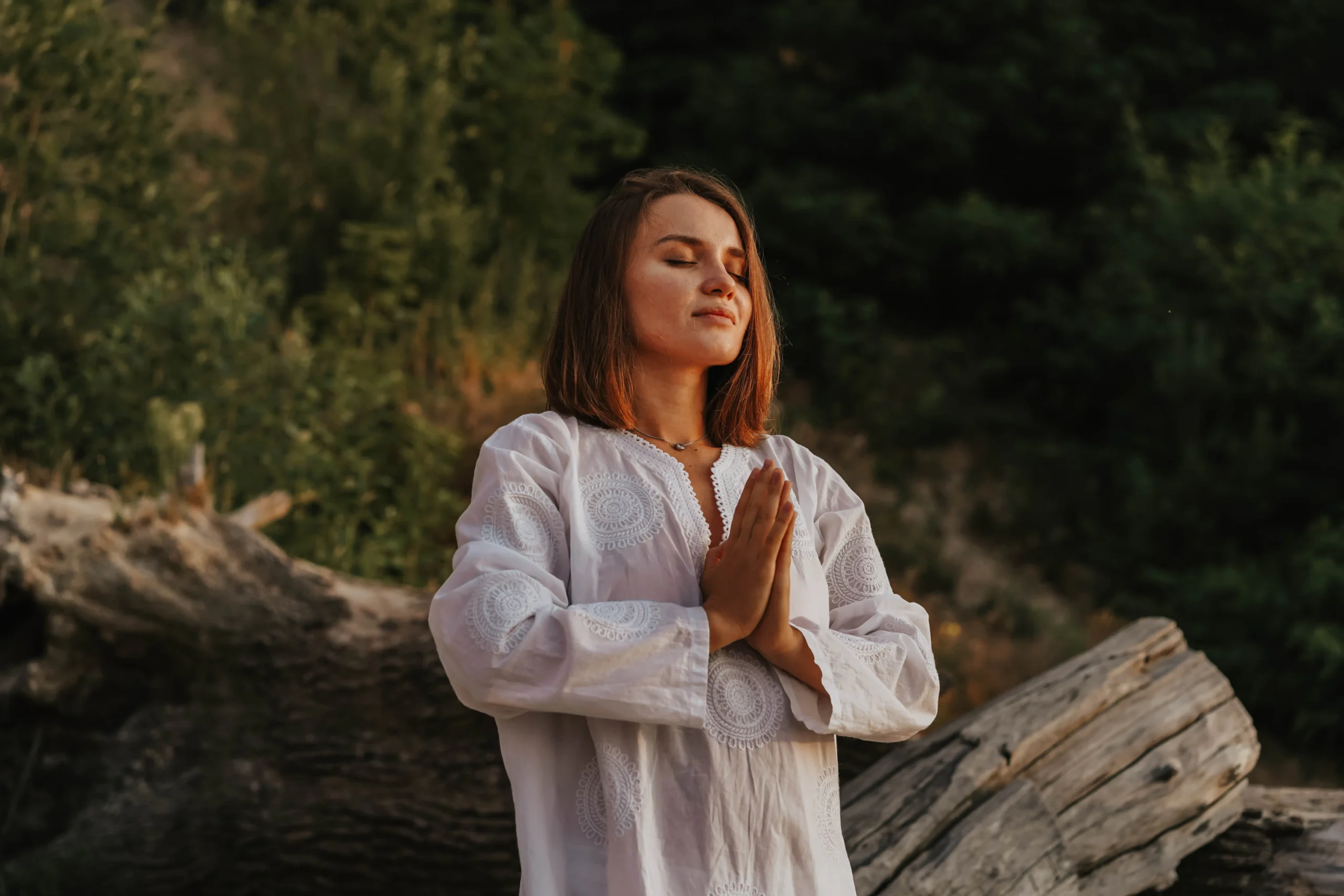 Woman in white dress meditating outdoors, seeking smooth skin solutions.