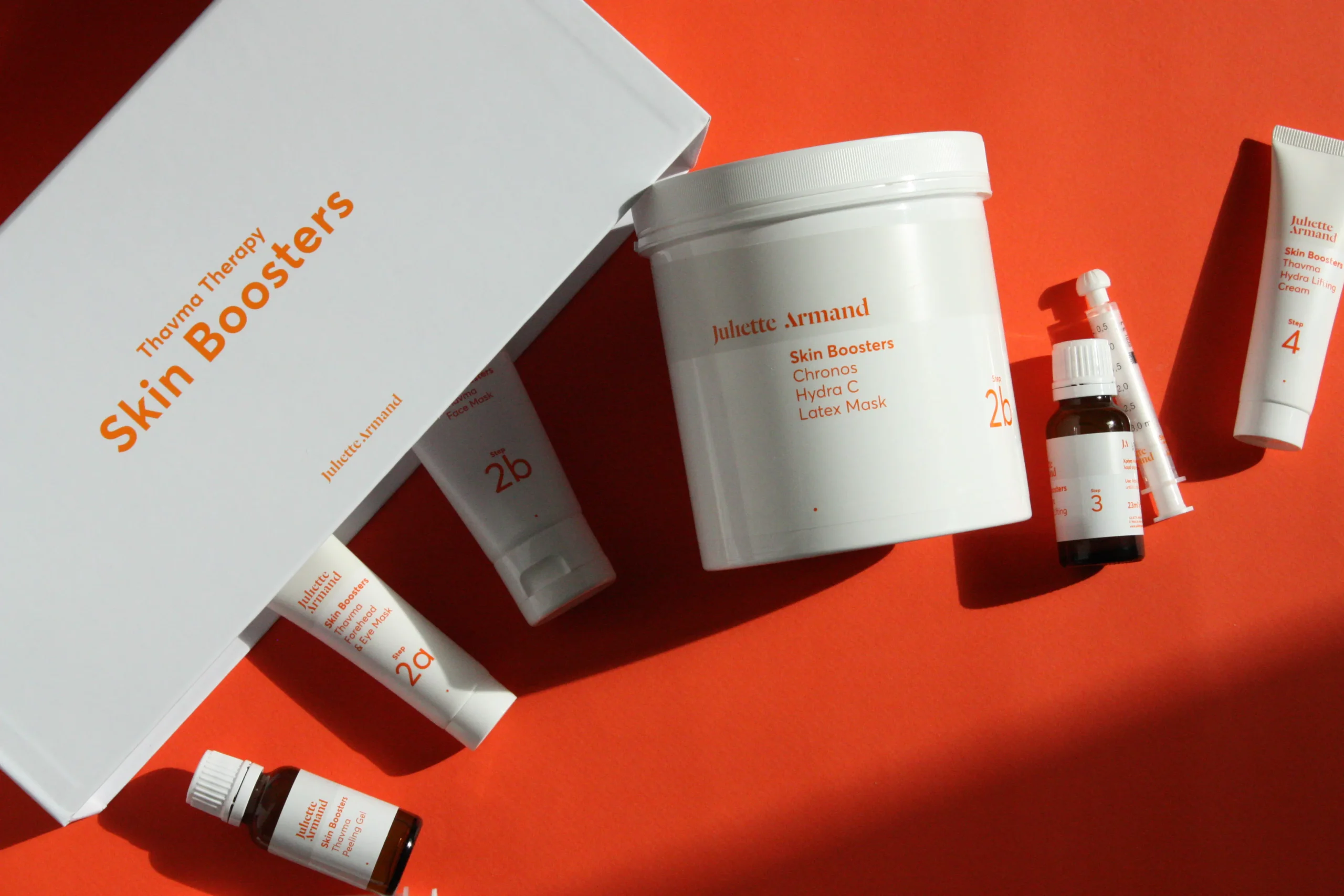 Juliette Armand Skin Boosters products for skincare post laser waxing on orange backdrop.