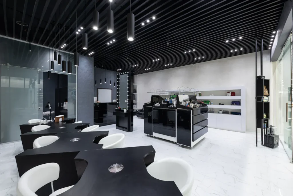 Modern beauty salon interior with black manicure tables and white chairs.