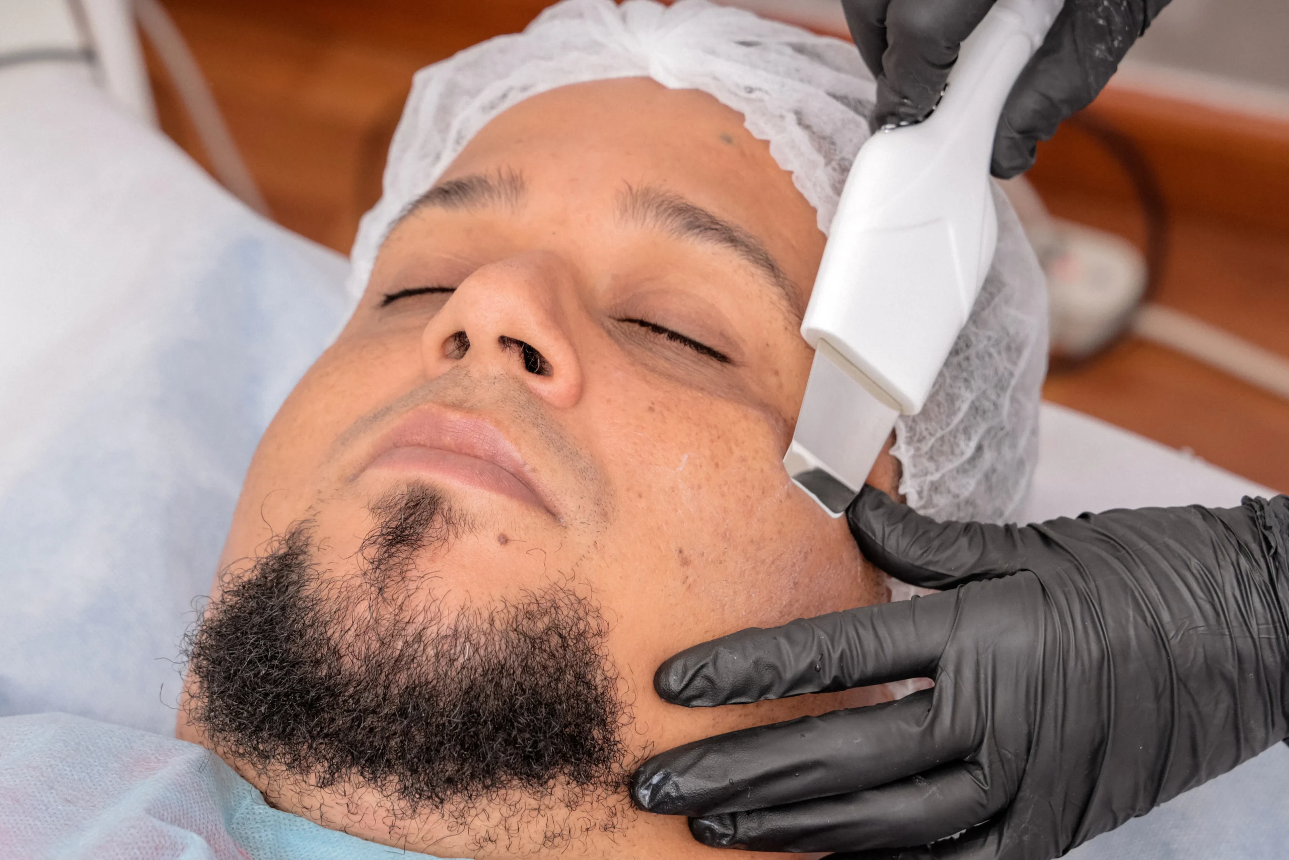 Man receiving facial beauty treatment at an Amsterdam beauty center with ultrasonic spatula.