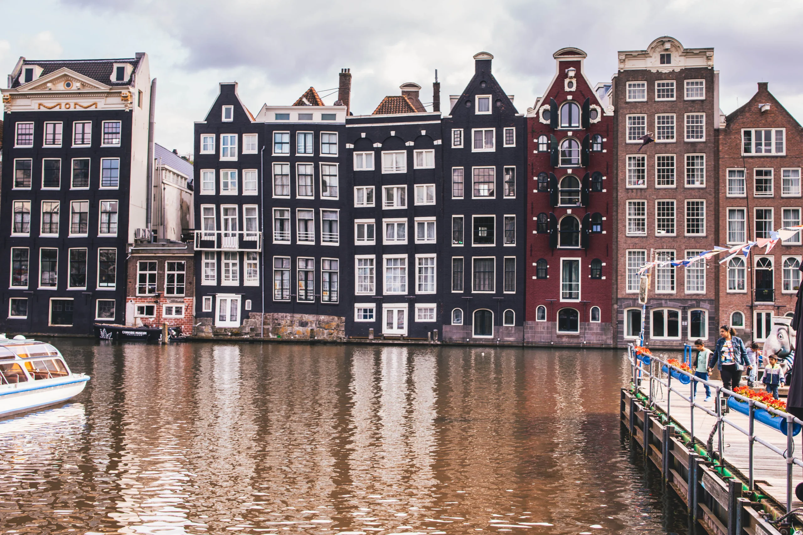 Amsterdam canal houses reflecting in the water on a cloudy day.