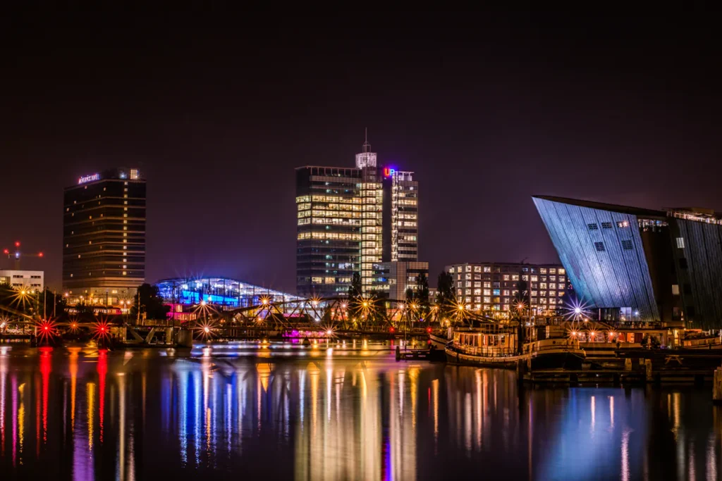 Amsterdam cityscape at night reflecting on the water, illuminated buildings and bridges