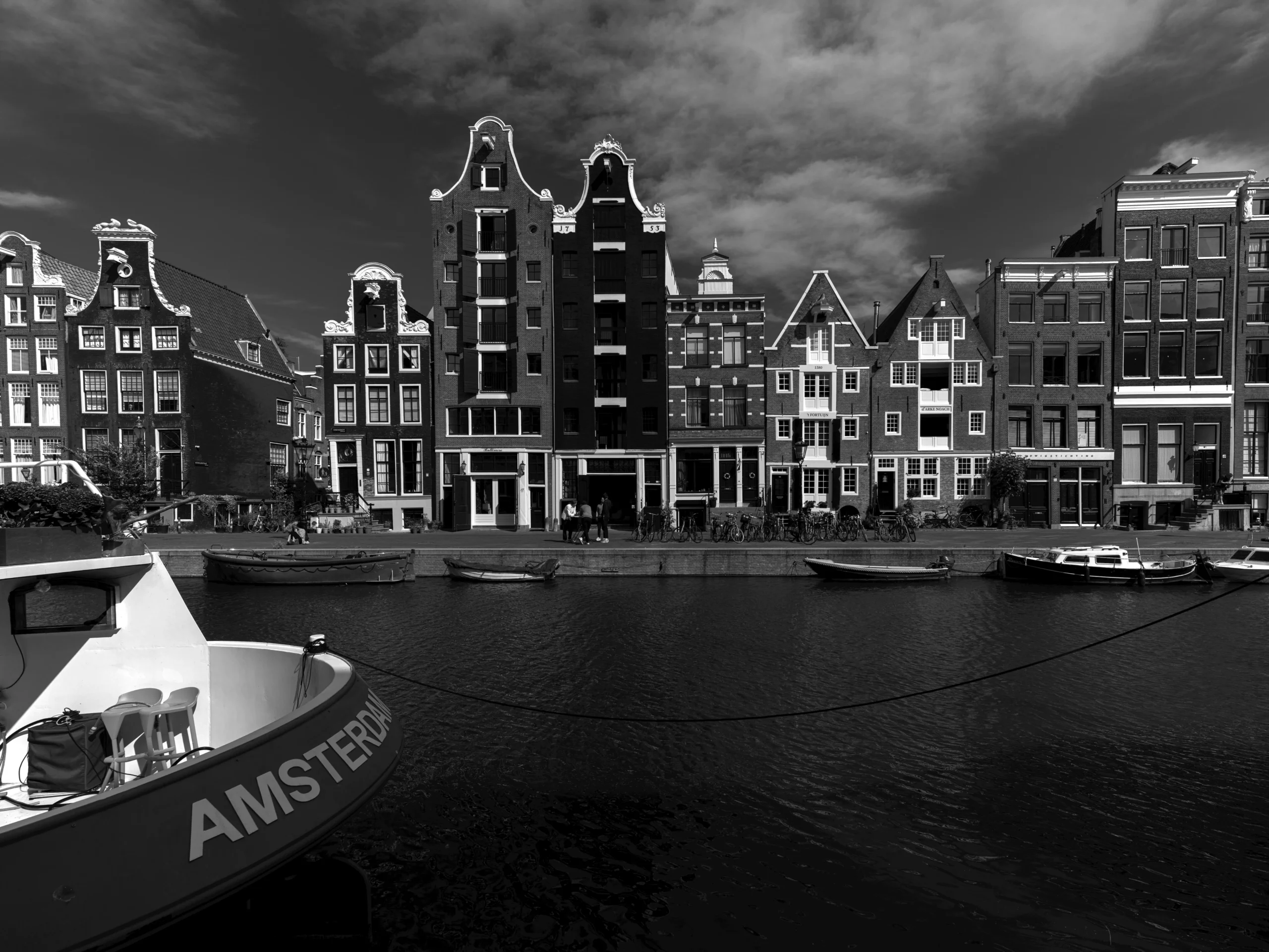 Black and white view of Amsterdam canal with traditional houses.