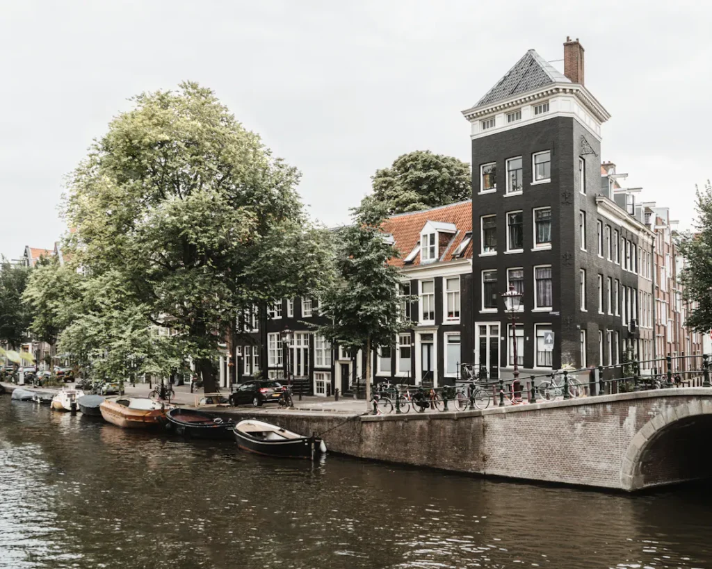 Amsterdam canal scene with boats, bicycles, and historic buildings.