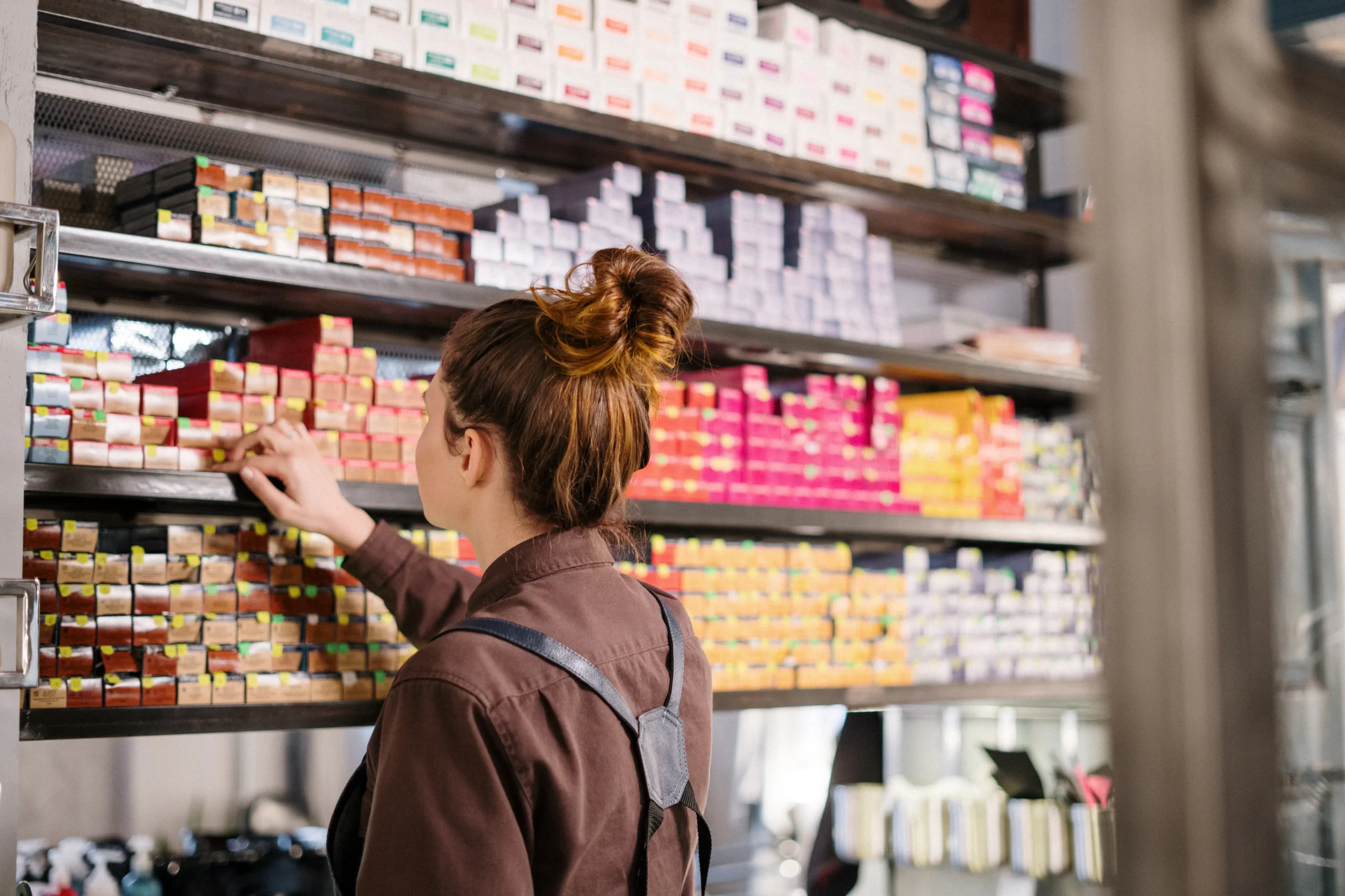 Hair stylist selecting hair color products on shelves in Amsterdam beauty salon.