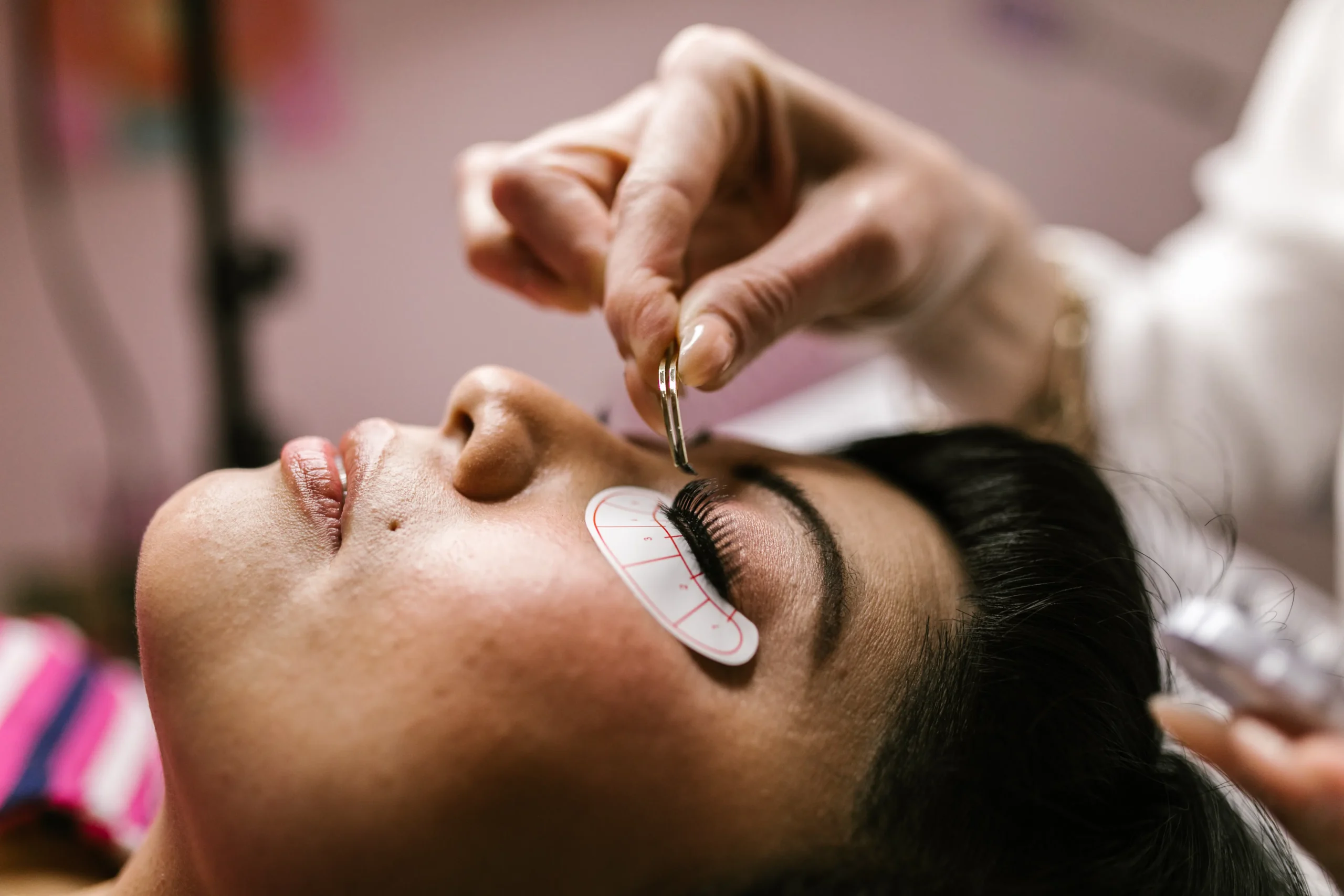 Woman receiving eyelash extensions at beauty salon in Amsterdam, close-up view.