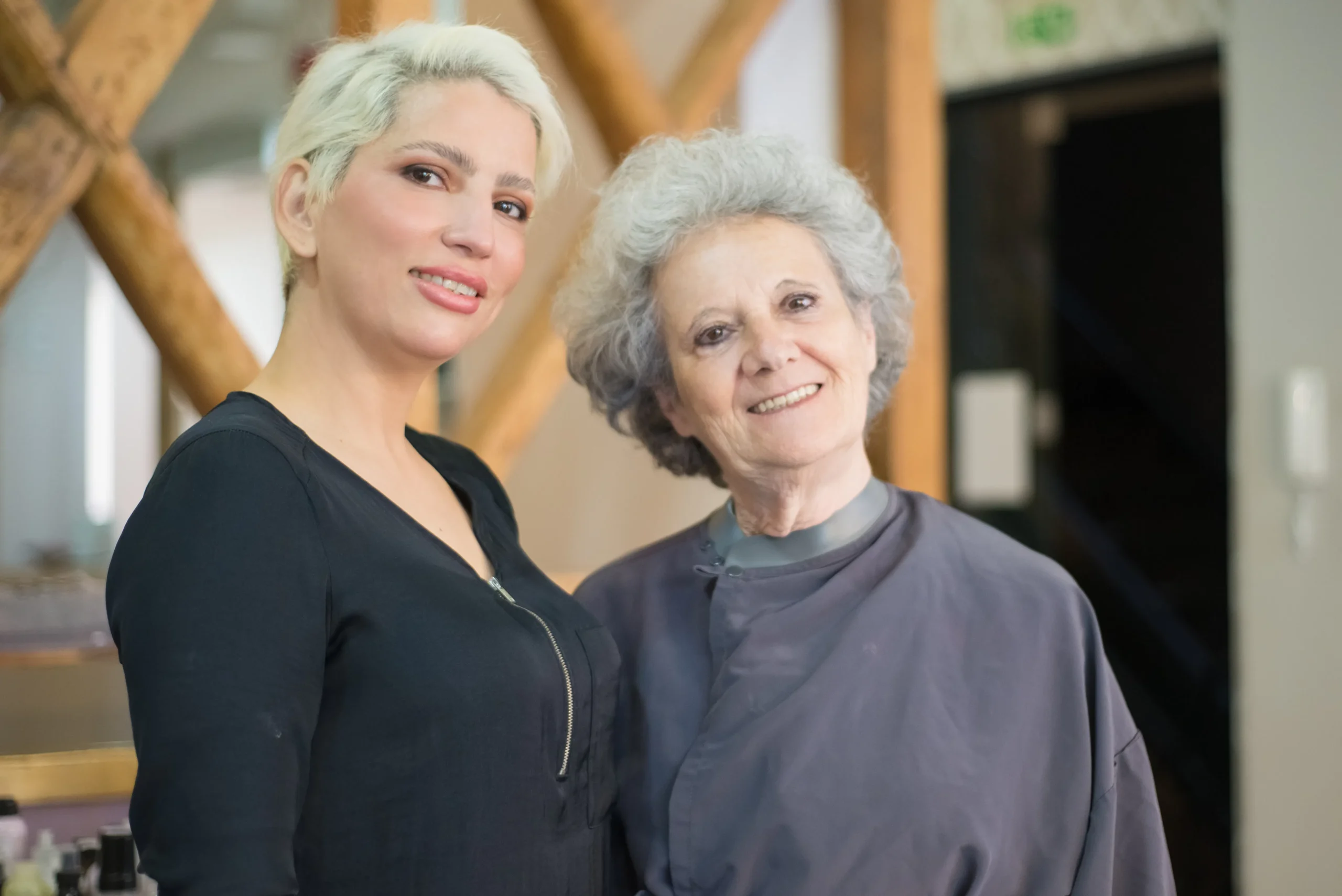 Smiling hairdresser and senior client at Amsterdam beauty salon.