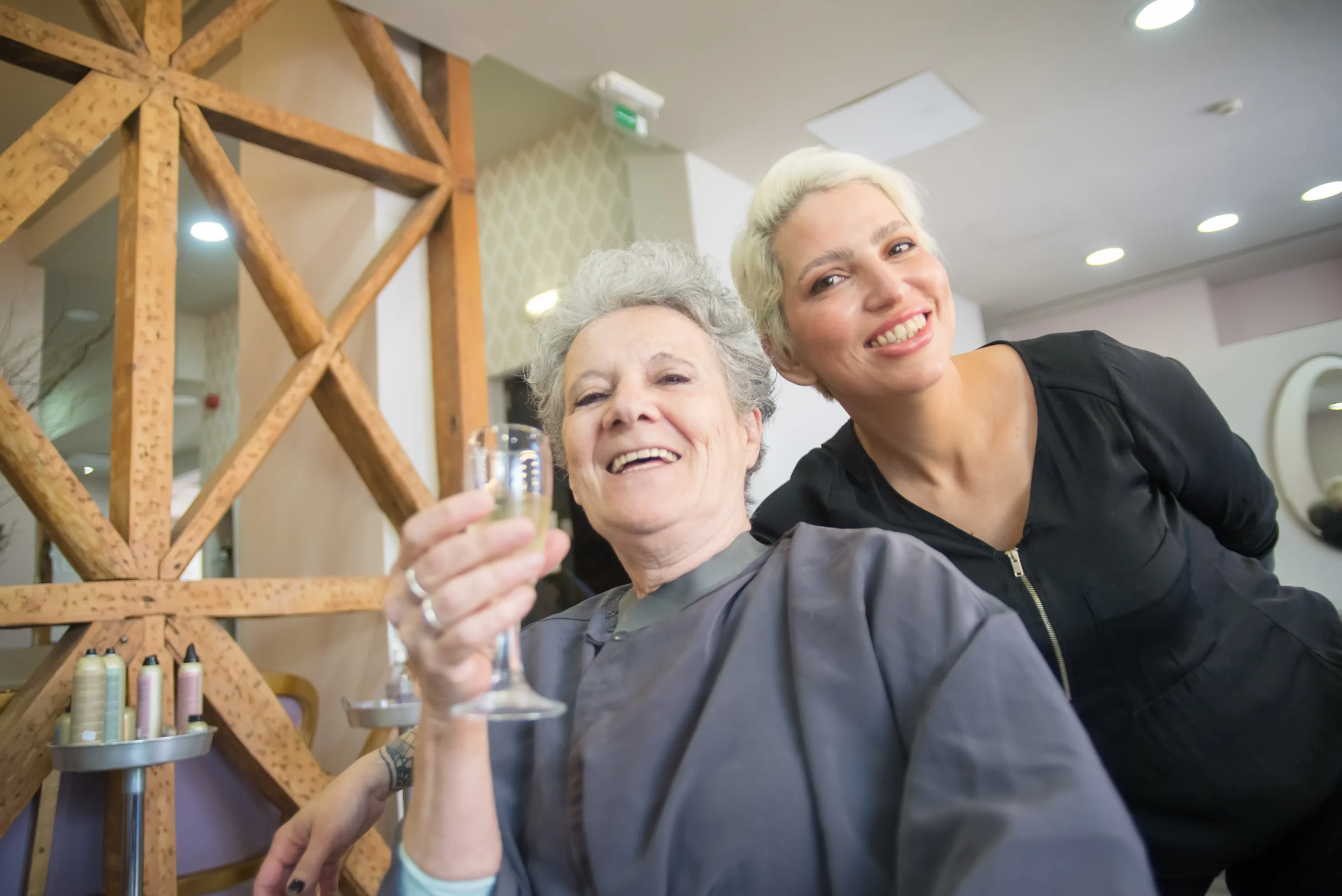 Client raising a champagne glass with a beautician at an Amsterdam beauty salon.