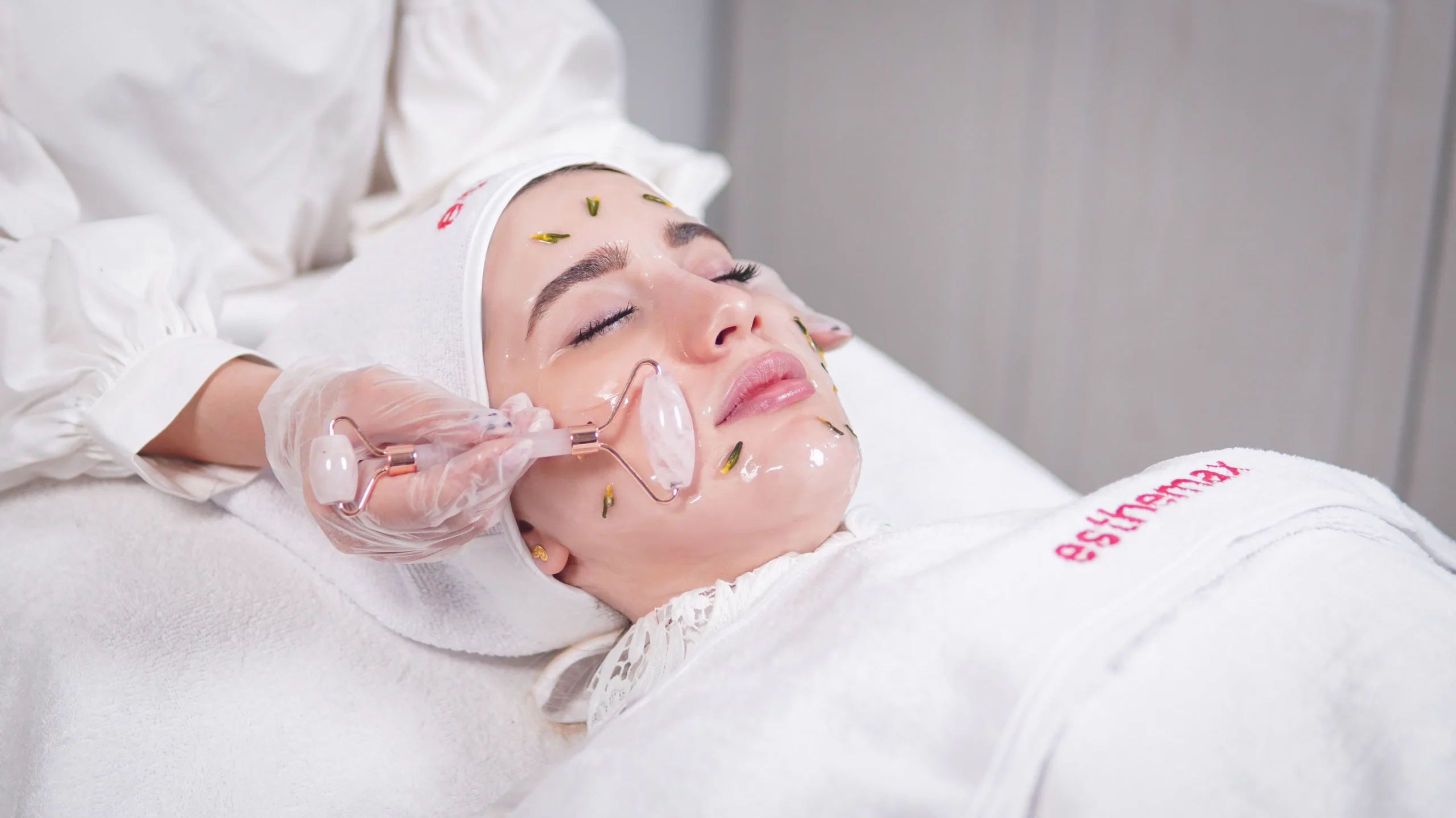 Professional skincare salon treatment featuring a rose quartz roller for facial skin rejuvenation.