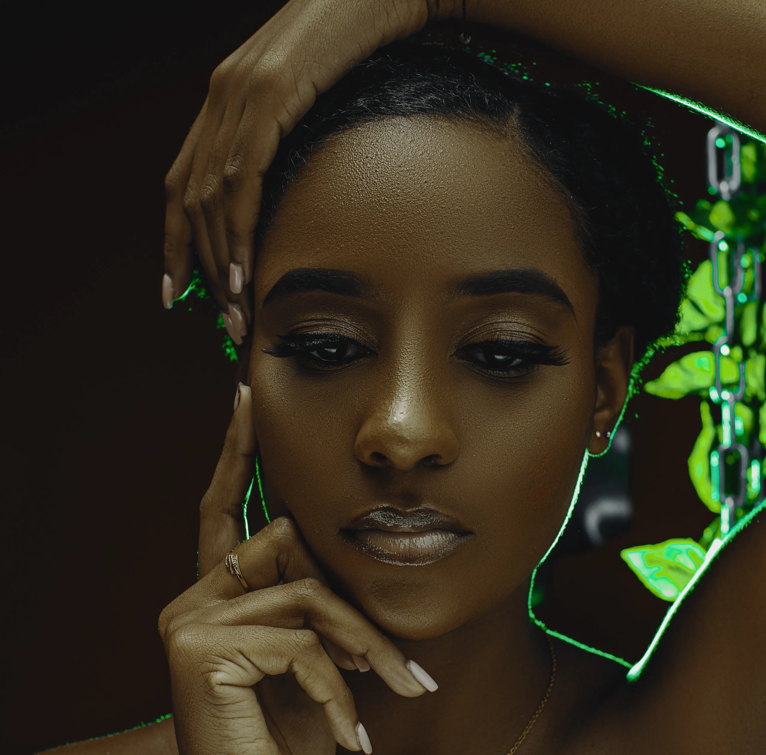 Close-up of a woman with elegant makeup, long lashes, and manicured hands, illuminated by green neon light, symbolizing a modern beauty treatment in Amsterdam.