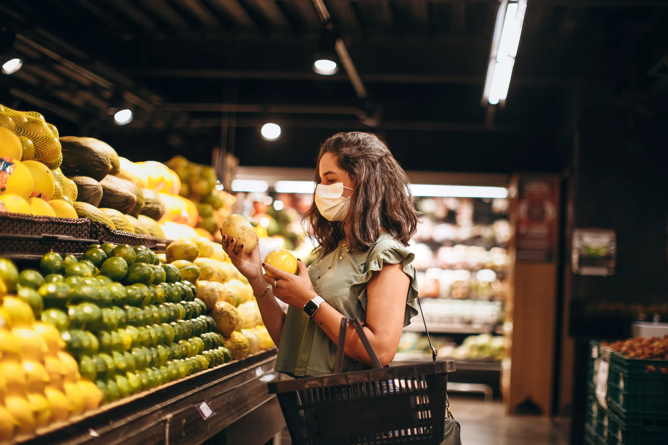 Woman wearing mask selecting produce at grocery store; unrelated to carbon peel advice.