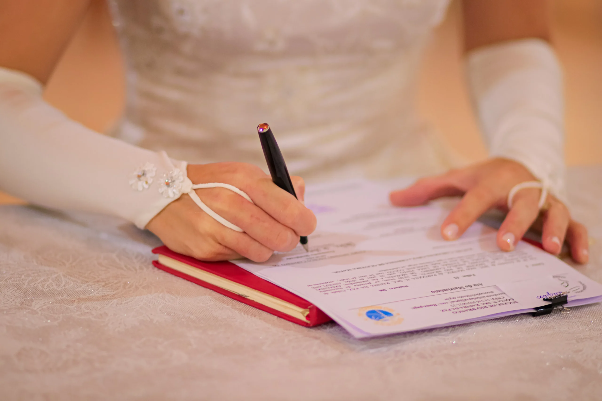 A bride signing a marriage document, representing professional beauty services for special occasions.