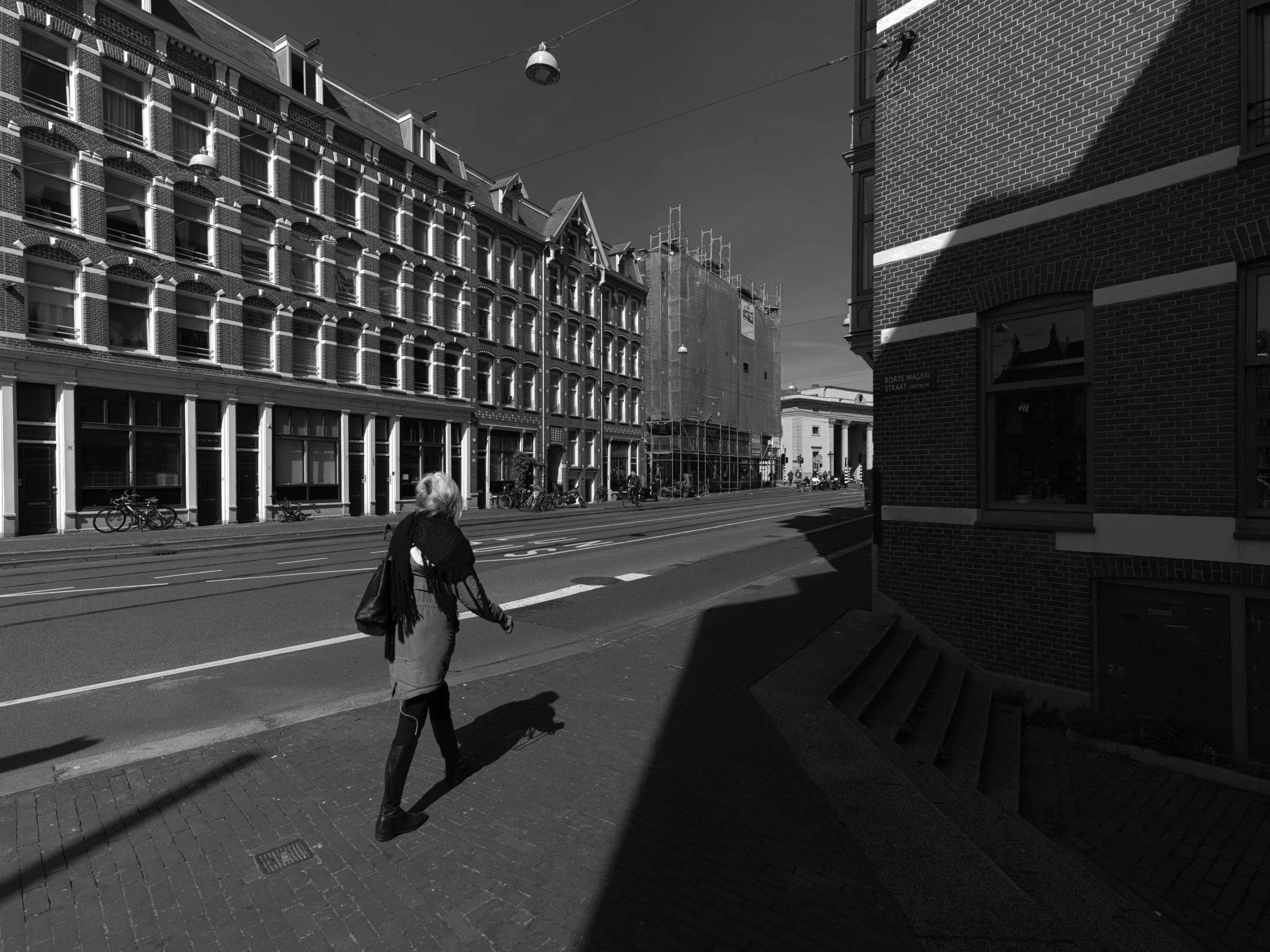 Black and white photo of a woman walking on a street in Amsterdam.