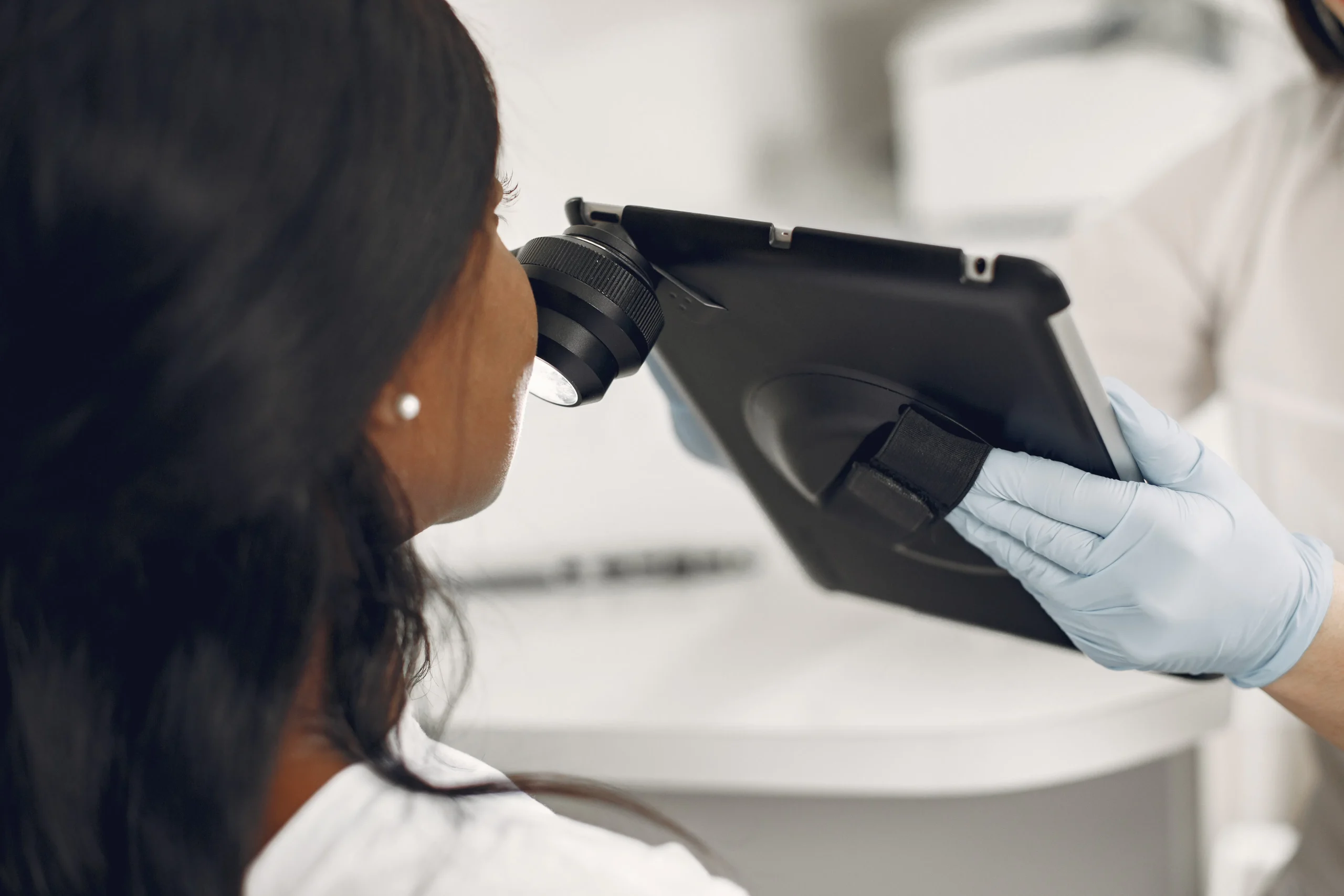 Dermatologist examining patient's skin with magnifying device, possibly before carbon peeling in Amsterdam