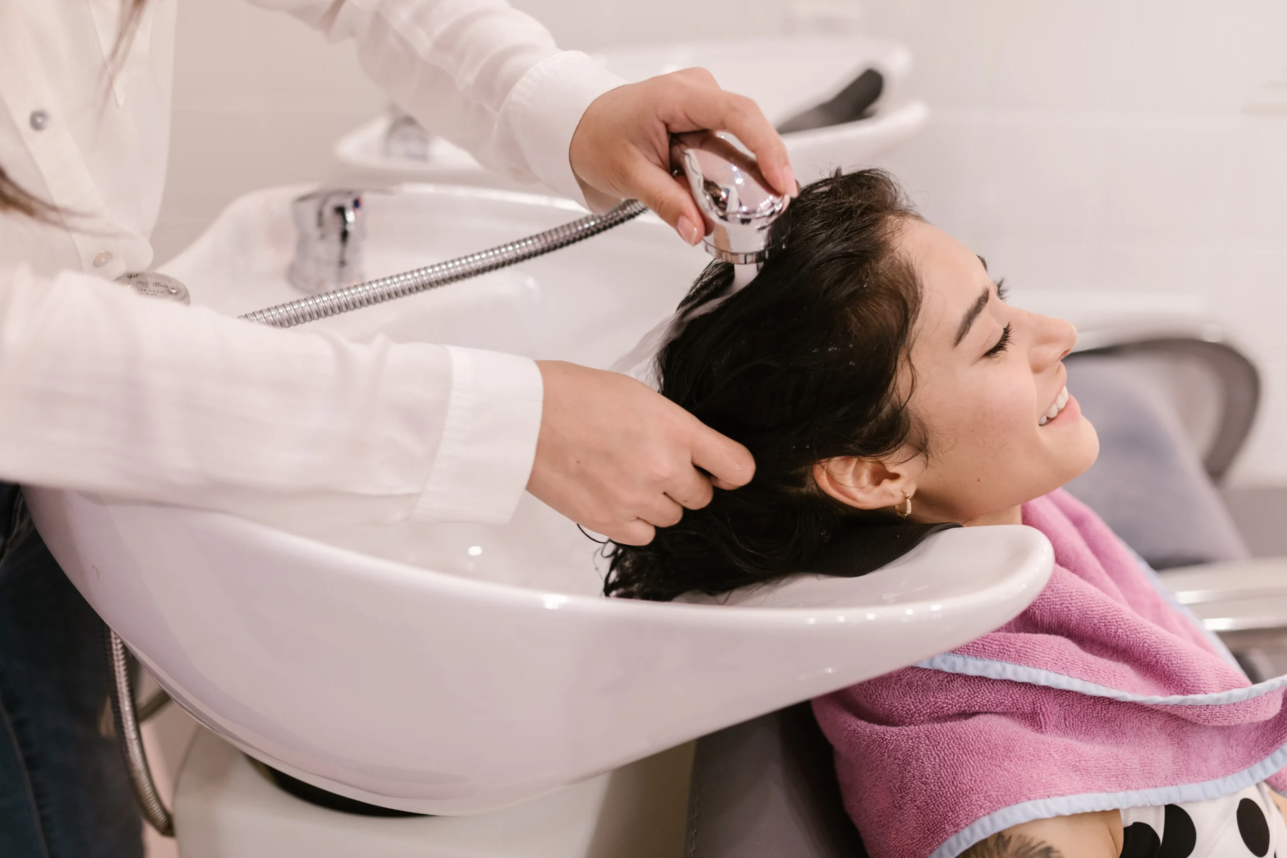 Woman smiles while getting her hair washed at an Amsterdam beauty salon.