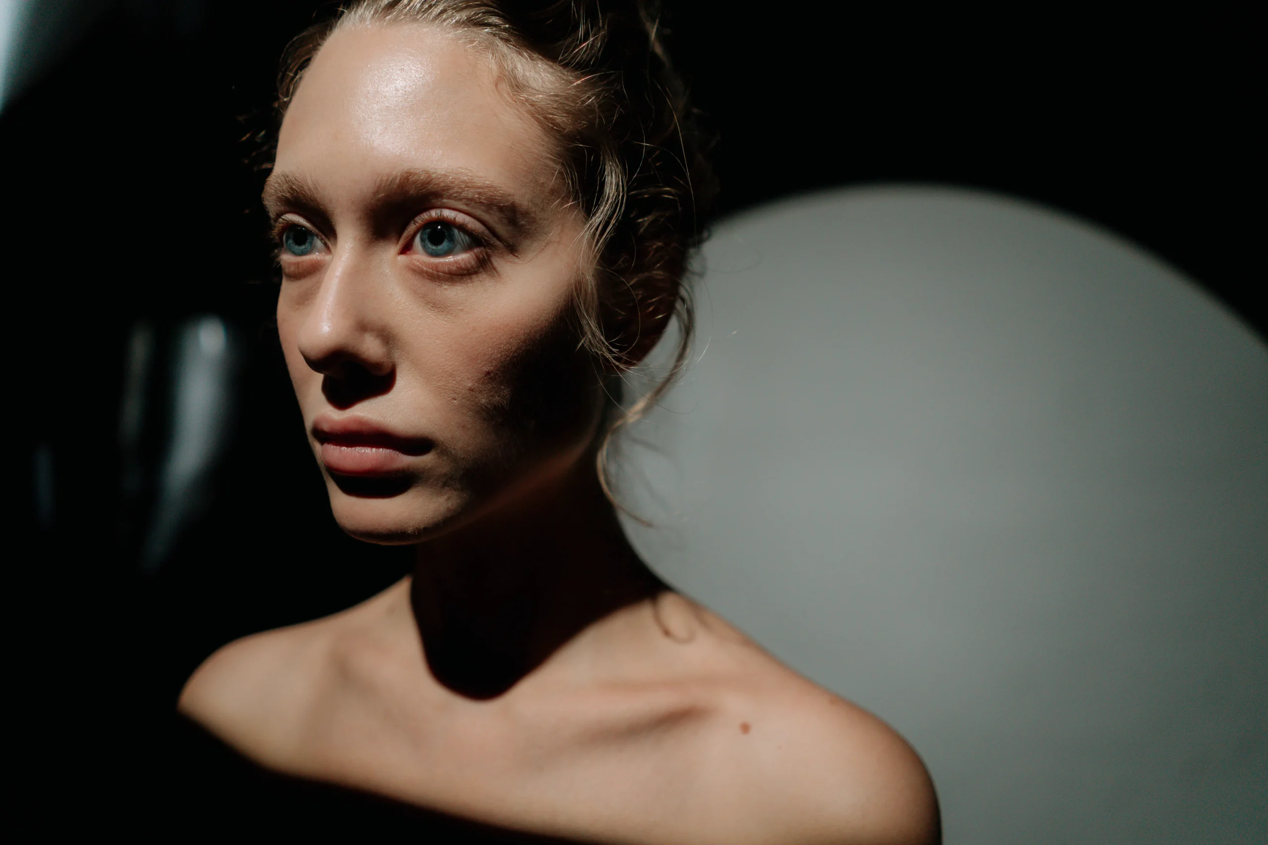 Close-up of a fair-skinned woman with blue eyes, dramatic lighting, for skin clarity.