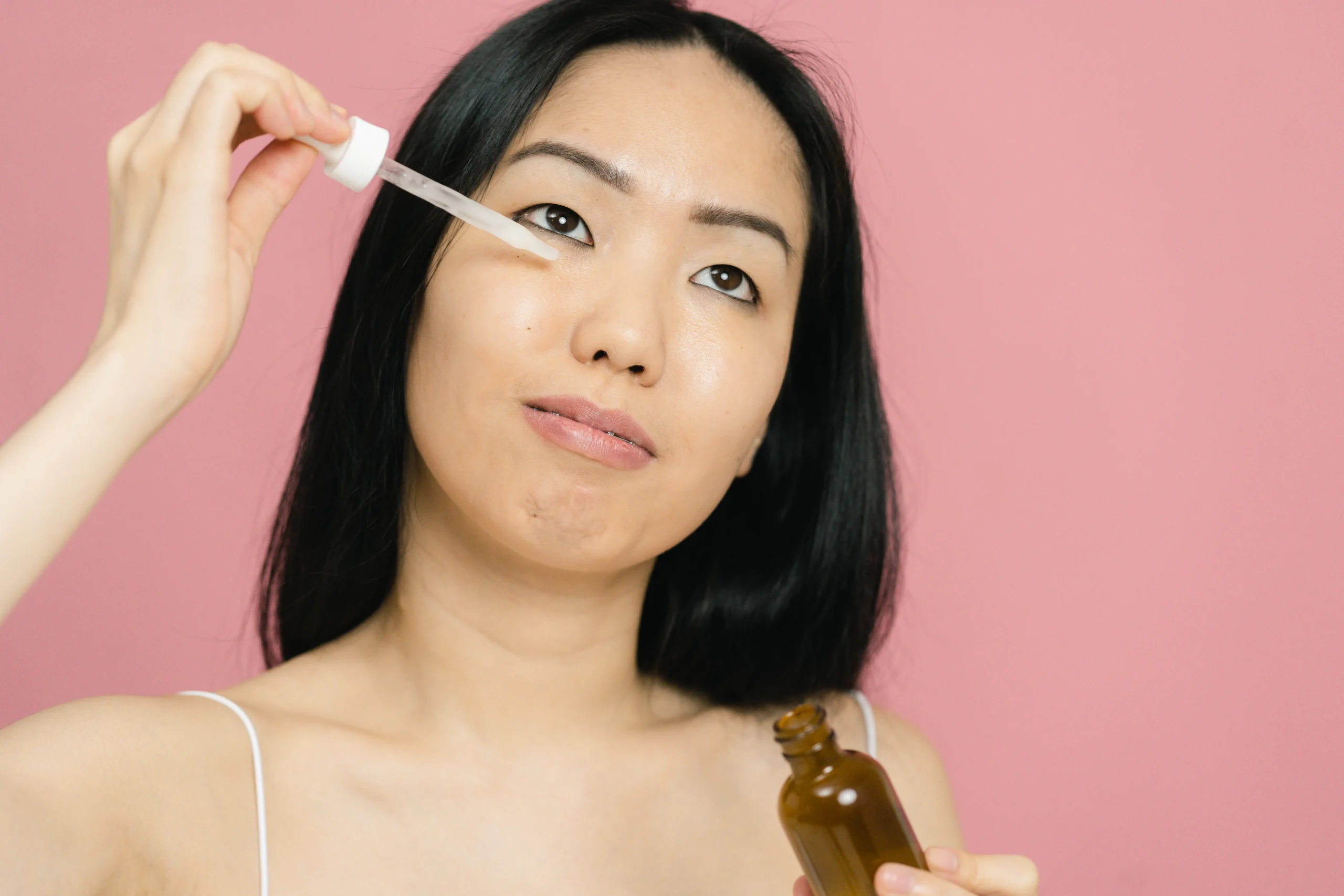 Young Asian woman applying facial serum with a dropper
